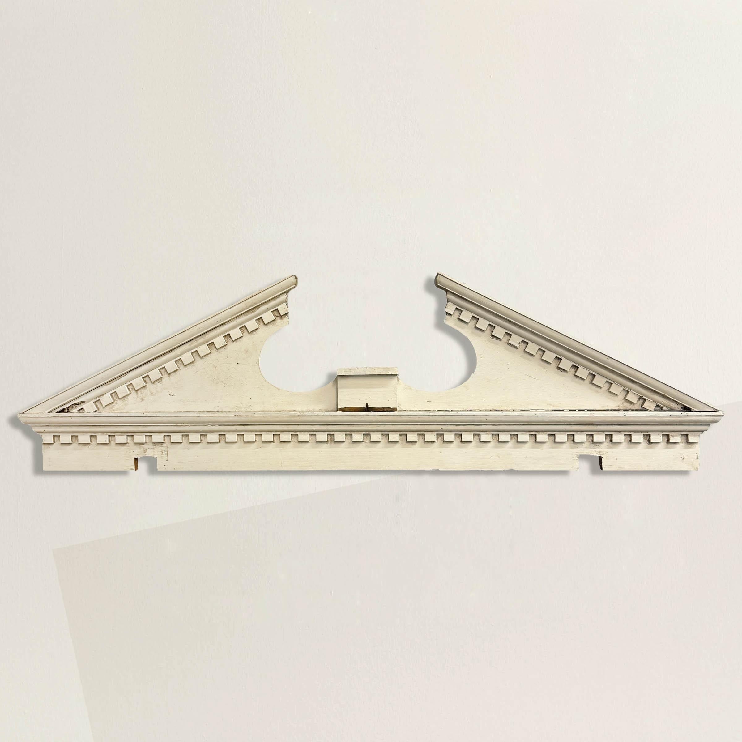 Crafted with meticulous attention to detail, this exquisite 19th-century American Greek Revival broken pediment is a classical architectural masterpiece featuring intricate dentil molding and is painted in timeless white, adding a touch of