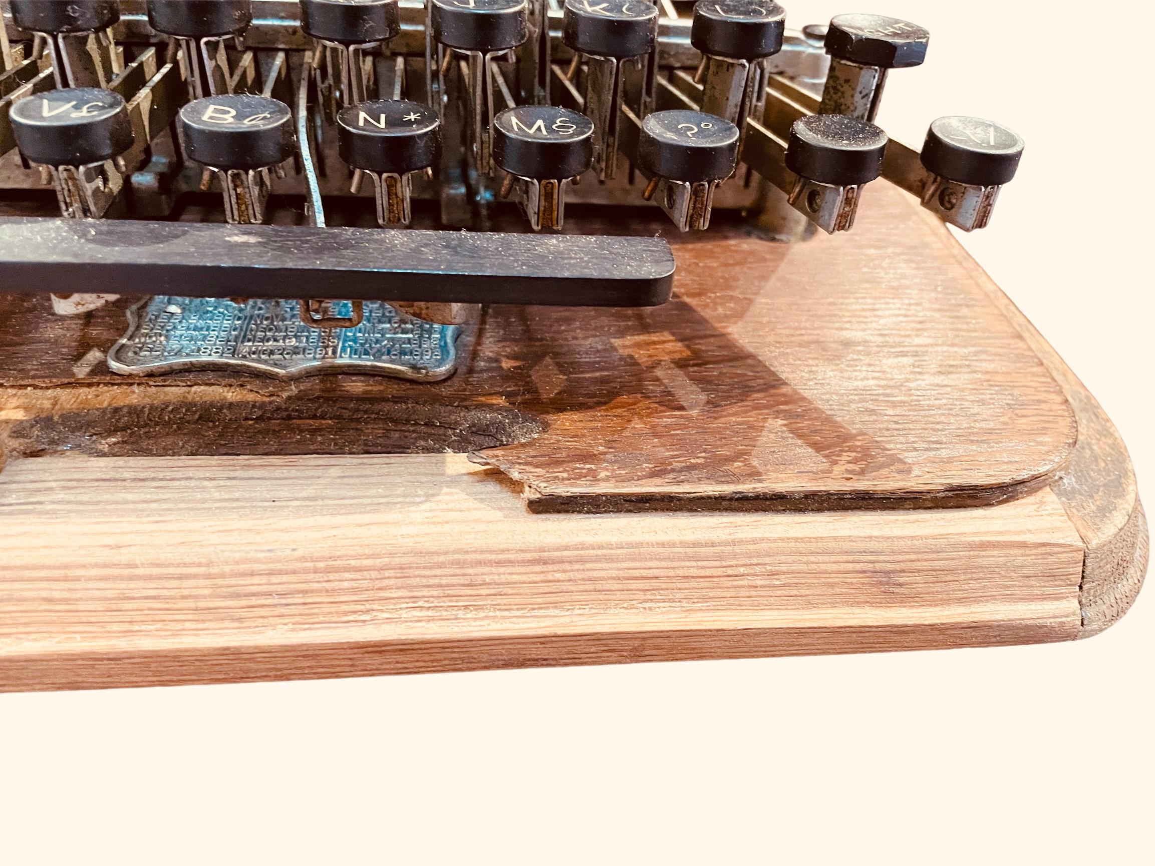 This is an American Hammond Typewriter. It was invented by James Bartlett Hammond and made by the Hammond Typewriter Company. It comes with its original oak wood top case  and repaired base board. It has an ebony celluloid keyboard. The Hammond