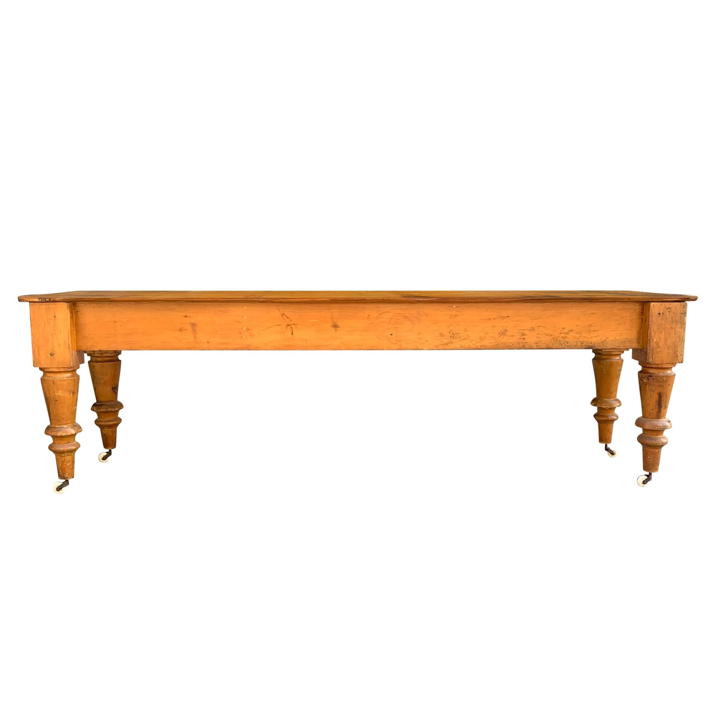 A wonderful 19th century American maple harvest table, probably from a butcher's shop or bakery with overly exaggerated turned tapered legs with porcelain casters and a well-worn top with one live-edge and one strait edge. Perfect for dining, but