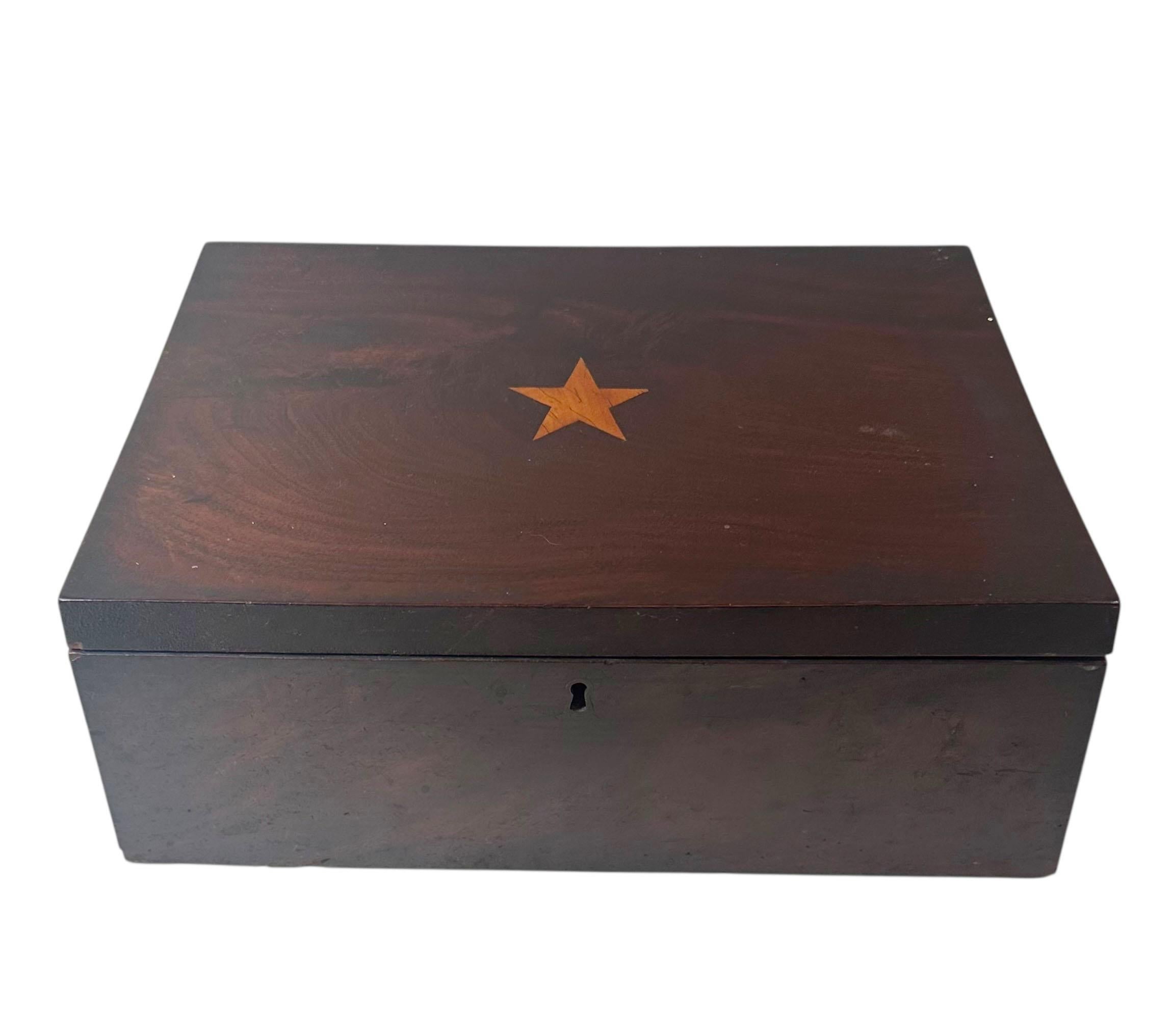 Hermoso joyero estadounidense del siglo XIX, chapado en tonos intensos y con un elegante motivo de estrella incrustado en la tapa. El interior tiene tres pulgadas y media de profundidad e incluye una bandeja con seis compartimentos, perfecta para