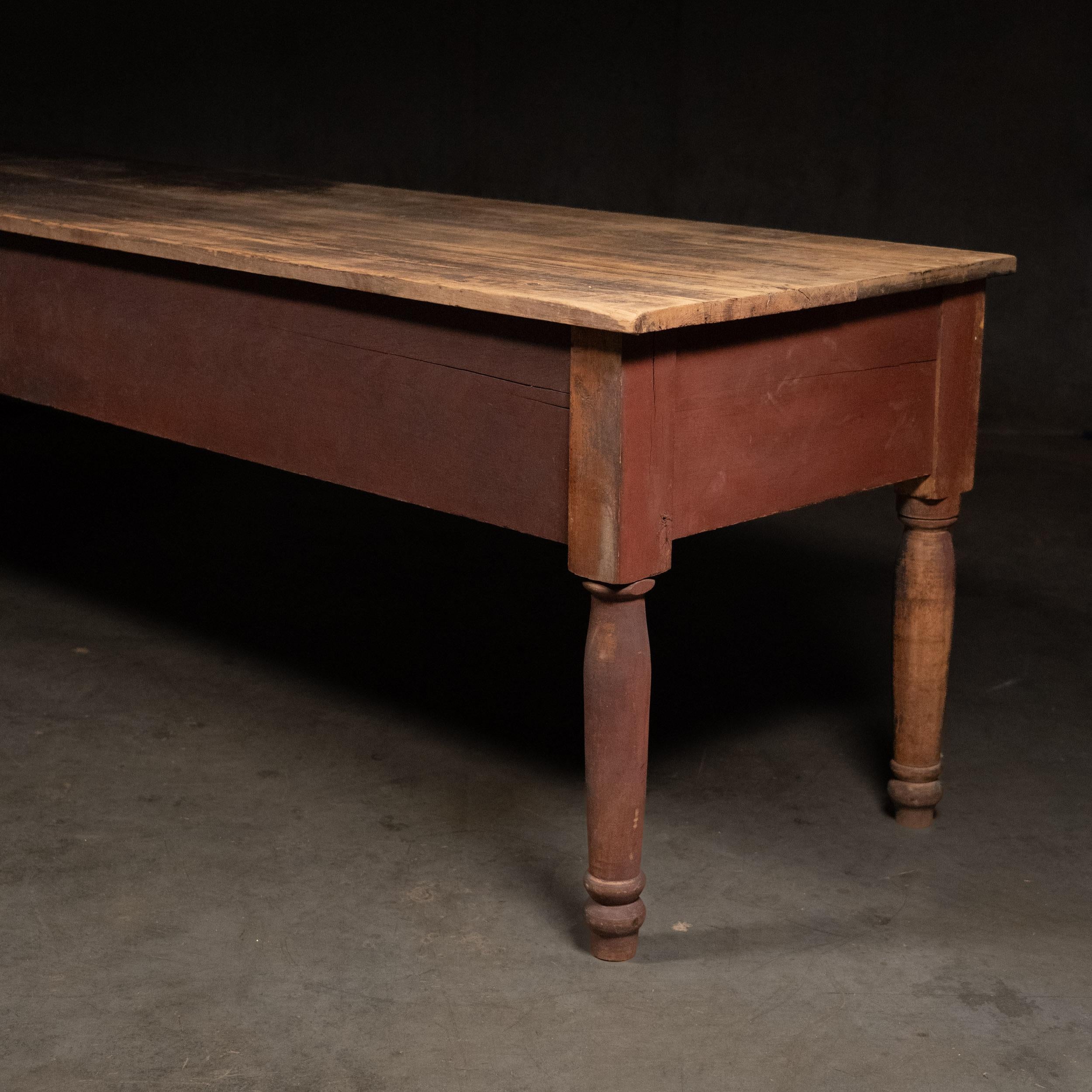 A great original work table used in a general store for sorting and displaying merchandise. Retains original red painted surface on turned legs  with scrubbed top.  The skirt is deep and the overall construction is pegged very solid and wood be a