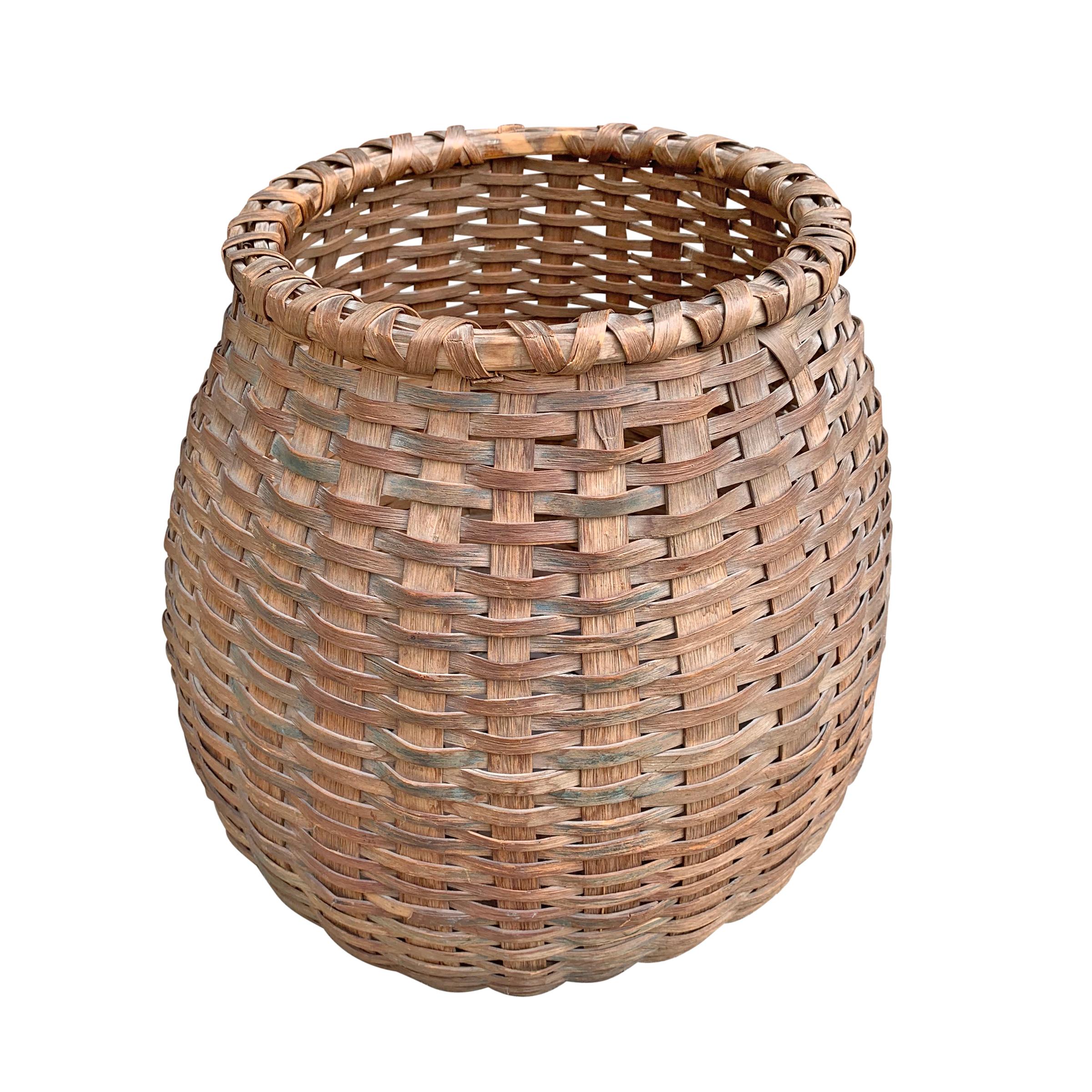 A beautiful 19th century American oak splint basket of ovoid form with a double-banded rim, traces of original green paint, and a twisted splint base. A chic waste paper basket!
