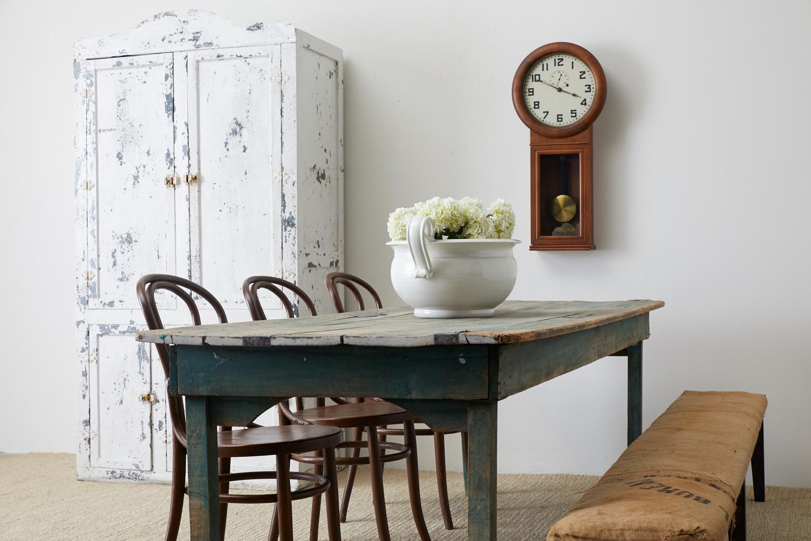 Rustic late 19th century classic American pine farmhouse work table or dining table. Features a long plank top conjoined to a teal green painted frame. The table is supported by square legs that taper on the ends. Beautifully aged and worn pine