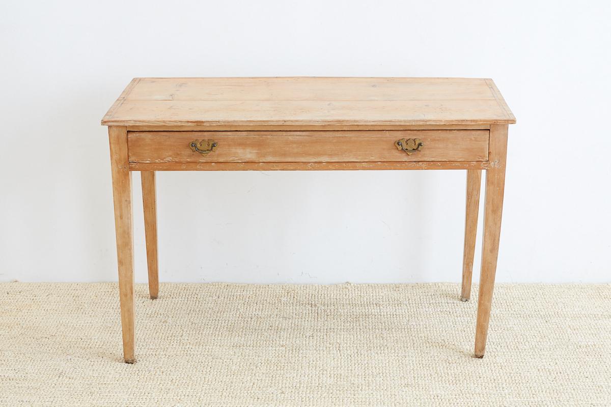 Rustic 19th century writing table or desk made from American pine. Handmade dovetail construction fronted by one large drawer with brass pulls. Perfectly cut drawer that slides easily. Supported by elegant tapered legs. Beautiful natural wax finish