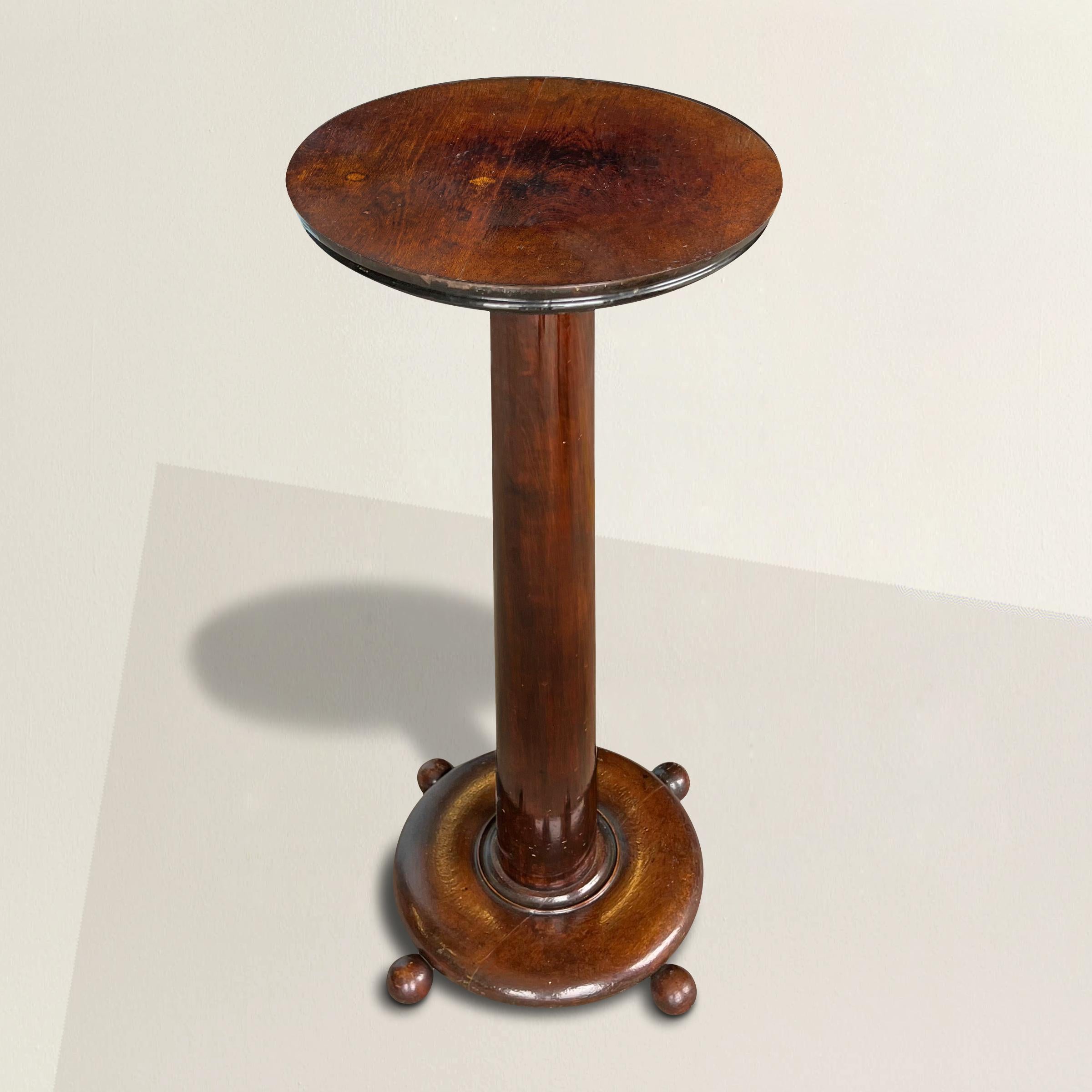 A lovable and modern-in-spirit 19th century American plant stand with a simple design with a round top supported by a tapered column on a base raised on four ball feet. Also makes a wonderful pedestal to display your favorite sculpture or objet