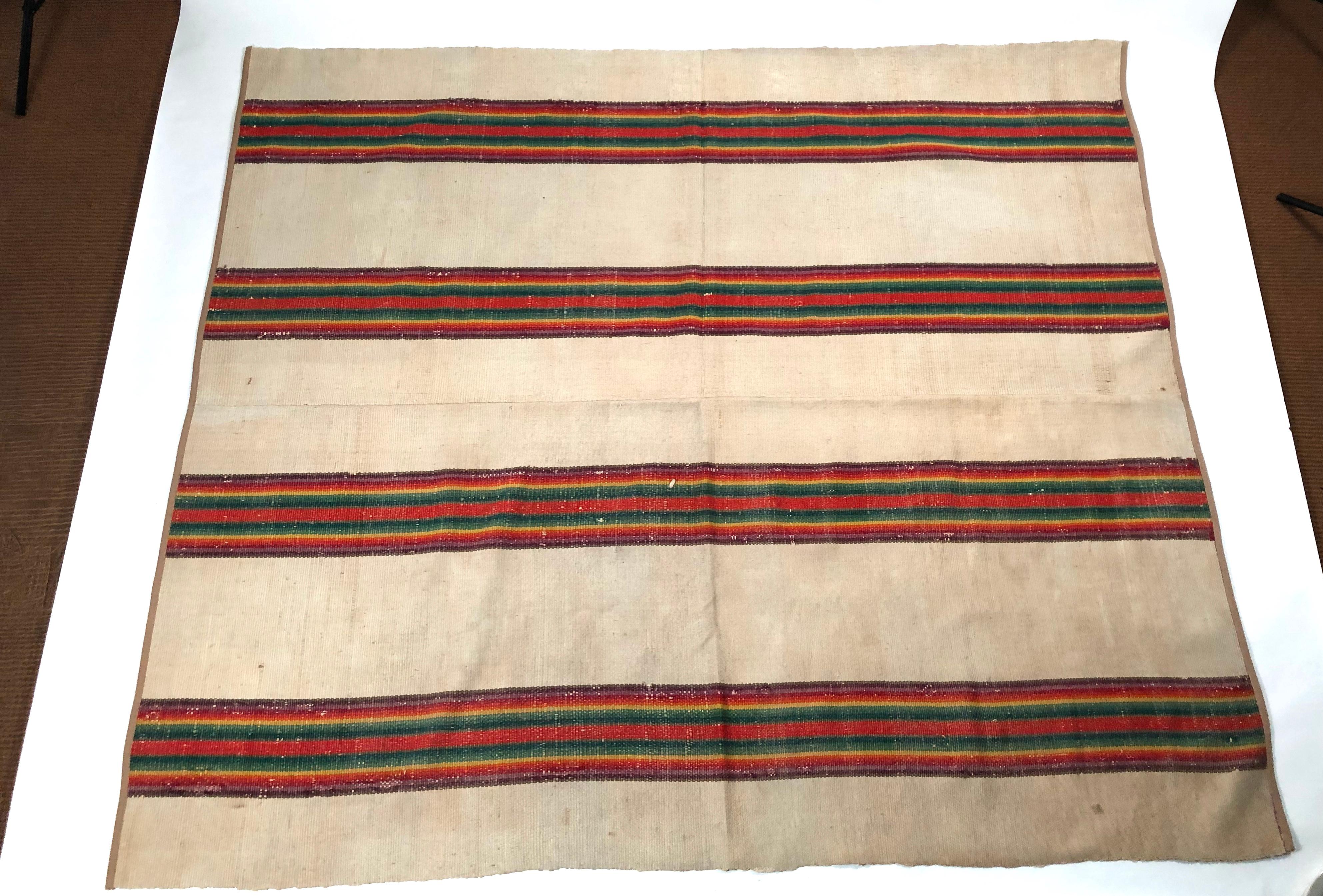 A 19th century American, reversible, Venetian striped flat-weave wool and cotton carpet, double sided, in vibrant, rainbow hued stripes on a cream colored field, in 2 sections, hand sewn together (as originally made), with tan canvas twill tape