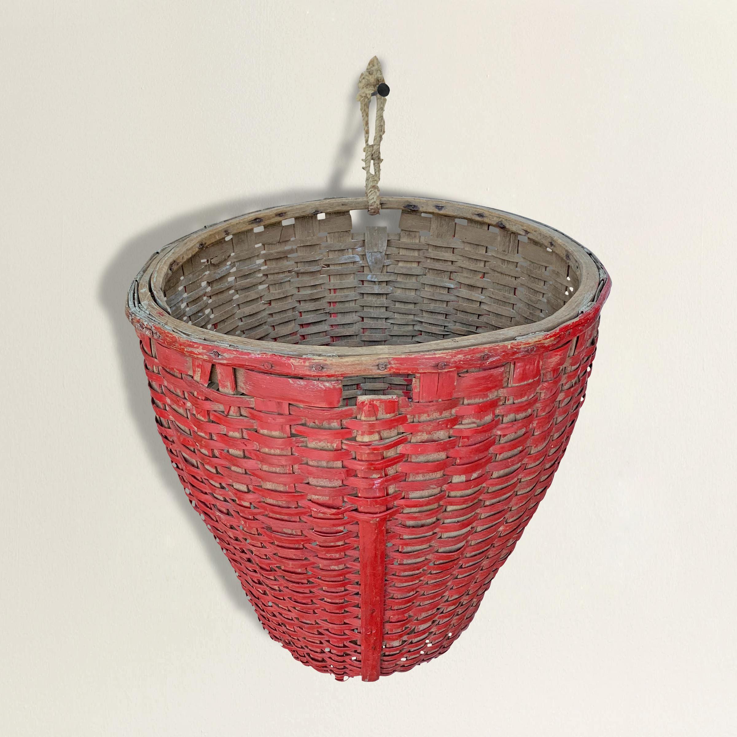 A fantastic 19th century American red painted oak splint round gathering basket with a tapered asymmetrical form making it perfect for hanging on a wall. Found in Western Massachusetts.