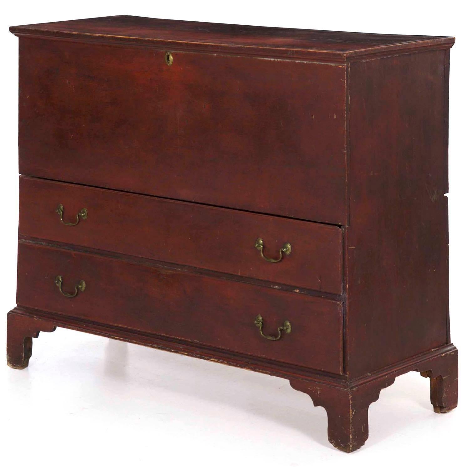 Retaining an old and almost certainly original red painted surface, this very striking mule chest of drawers is austere and primitive in form. The top lifts over large iron hinges to reveal a blanket storage chest over a pair of full width drawers