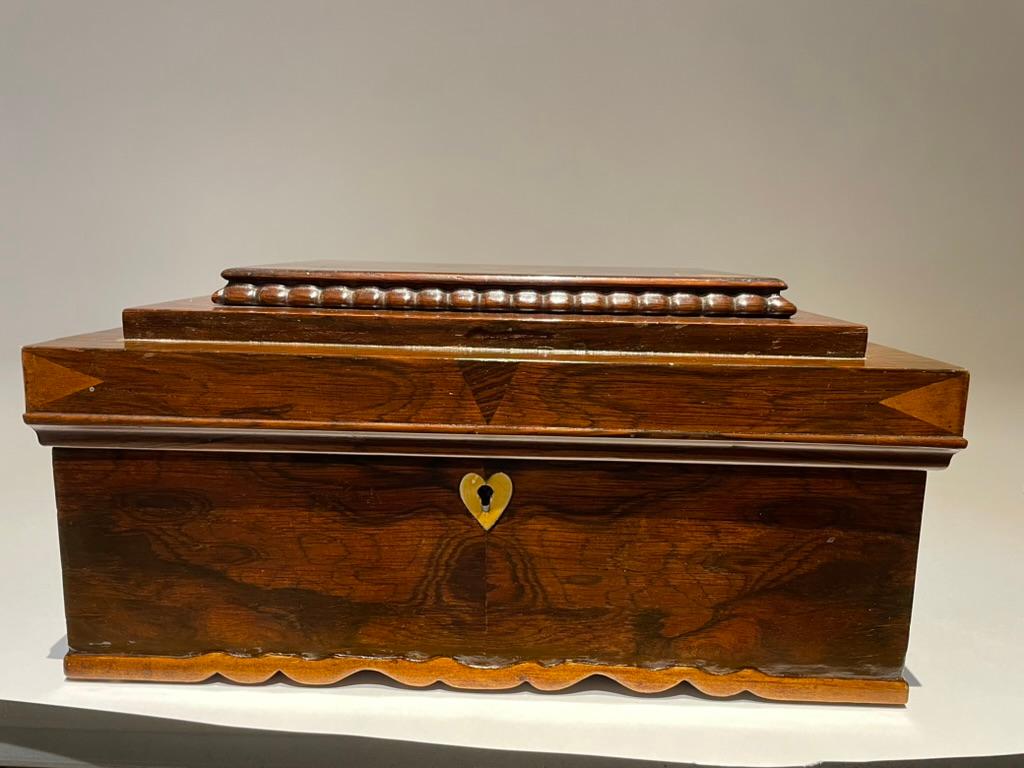 A beautifully made hand carved rosewood and fruit wood box with heart shaped bone escutcheon.The whimsical interior lined with paper carpet pattern from Peterson's Magazine 1876. The sides with reverse painted blue glass panels with floral motifs.
