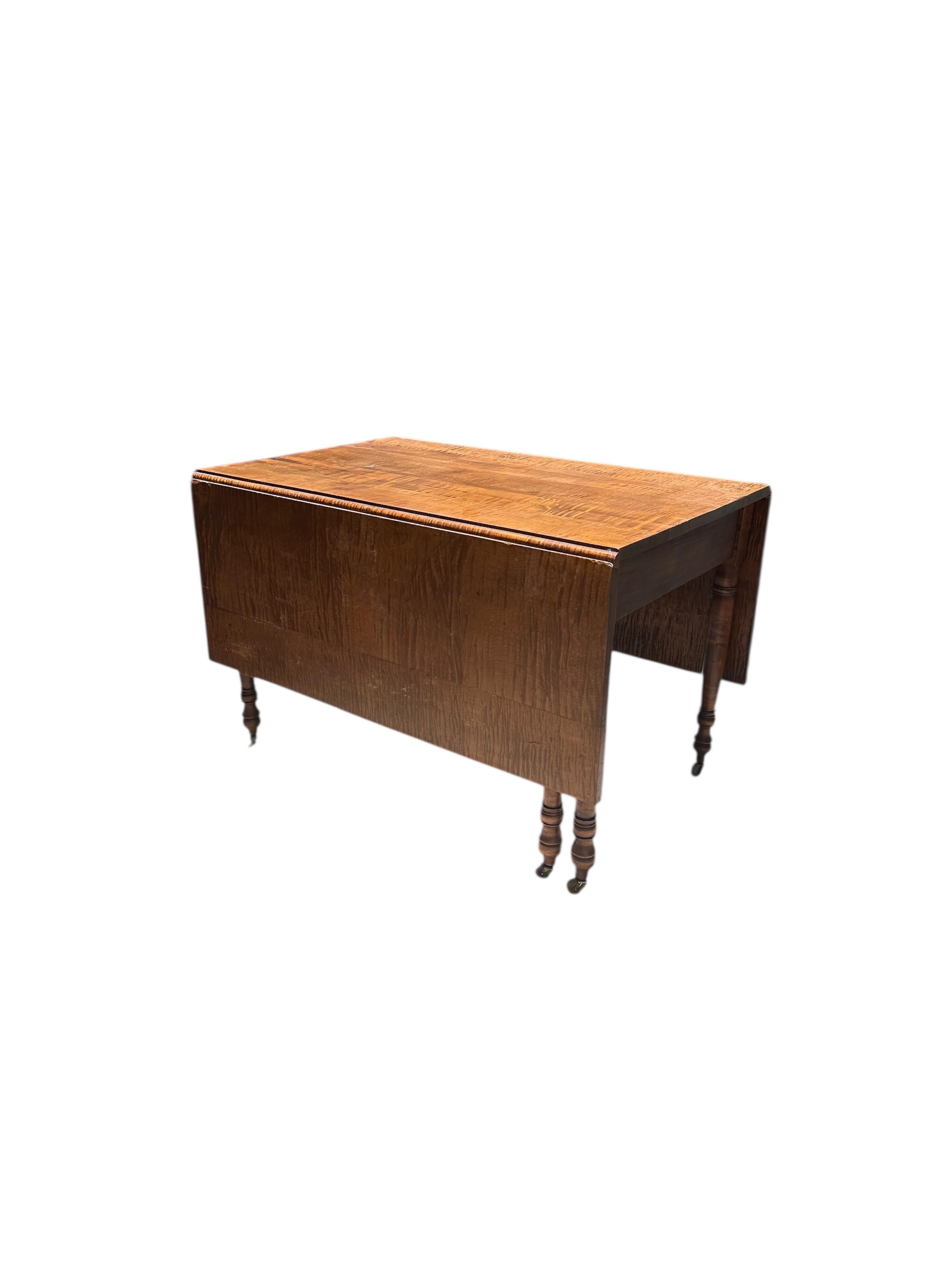 19th Century American Sheraton Tiger Maple Drop Leaf Dining Table

Spectacular tiger maple drop leaf dining table in American Sheraton style.
The top has two hinged leaves above a straight apron. Six tapered and turned gatelegs end in wood casters.