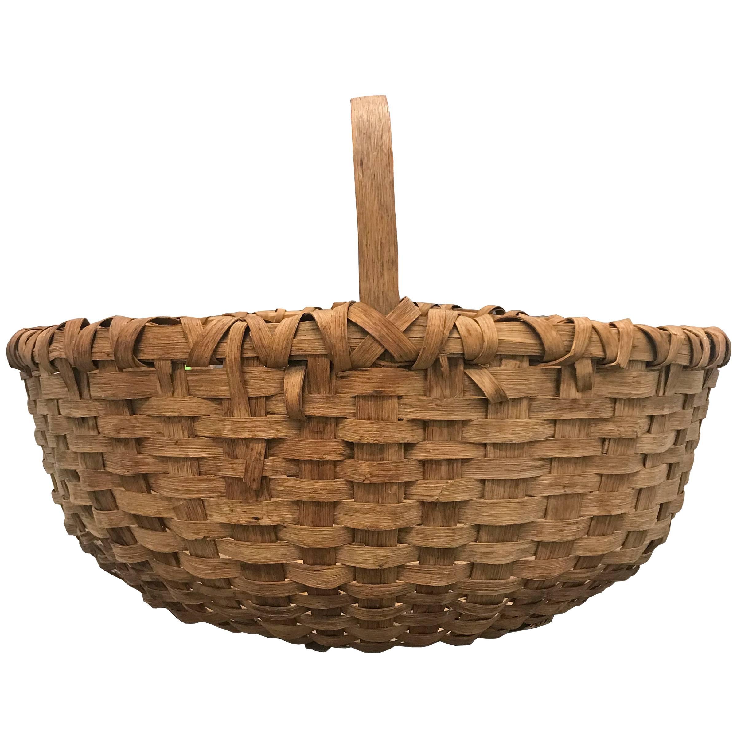 A large 19th century American splint oak gathering basket with one long bent-oak handle, a double banded rim, and a large belly. Found in New England.