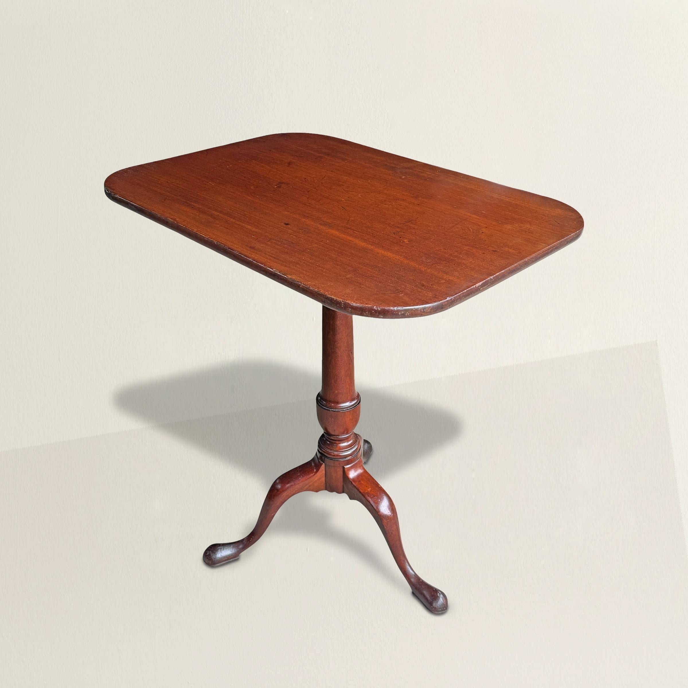 An early 19th-century American mahogany tilt-top table, carved in the Queen Anne style, quietly rewrites the familiar script. Most tilt-tops of the period were round—perfectly polite, perfectly expected. This one, however, asserts itself with a