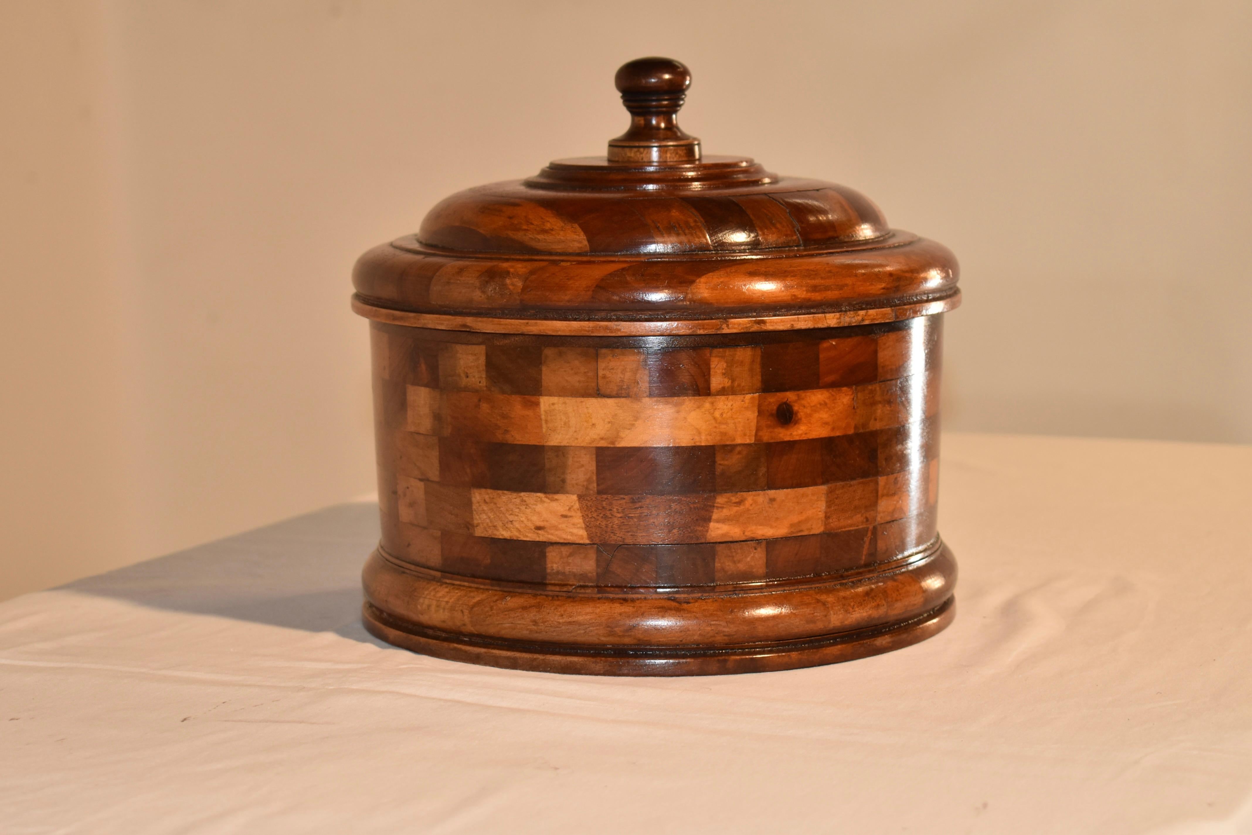 19th century large treen lidded box made from birch, walnut, cherry, mahogany, and oak.  The wood is layered in a design which is very pleasing with contrast of color and shape of each block of wood.  The top has a turned handle and is turned ads