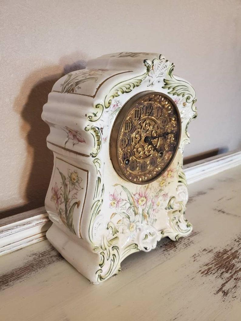 An exquisite antique Ansonia Rococo style mantel clock from the late 19th century. Handcrafted in the United States by the Ansonia Clock Company, dated June 18, 1882, featuring white Royal Bon porcelain case with applied floral motifs, encasing an