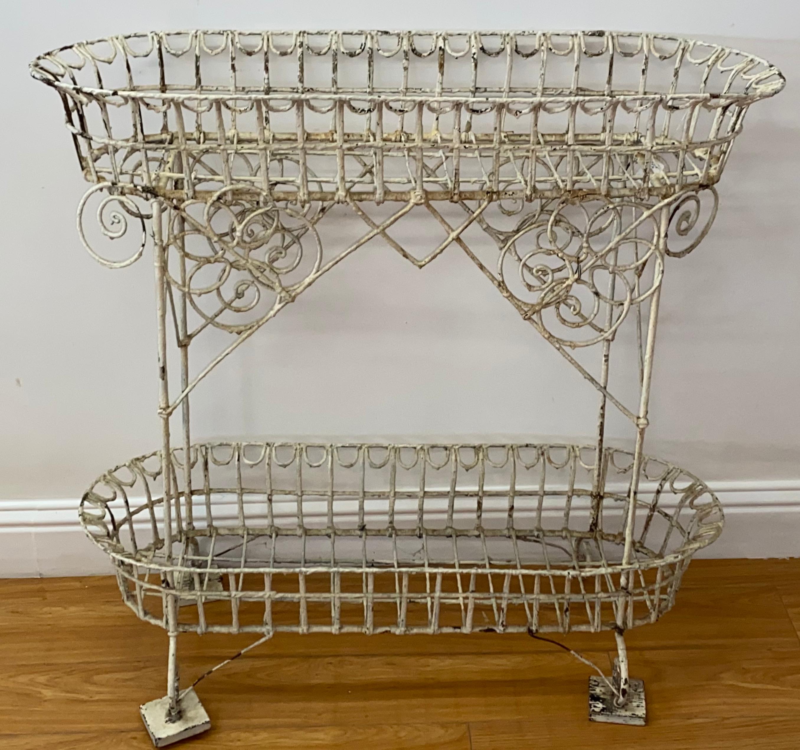 19th century American wrought iron plant stand

Hand made plant stand with one drip tray that can be used on the top or bottom

Painted white

Two of the feet have wooden blocks, easily add two more, or remove 

Measures: 36.5