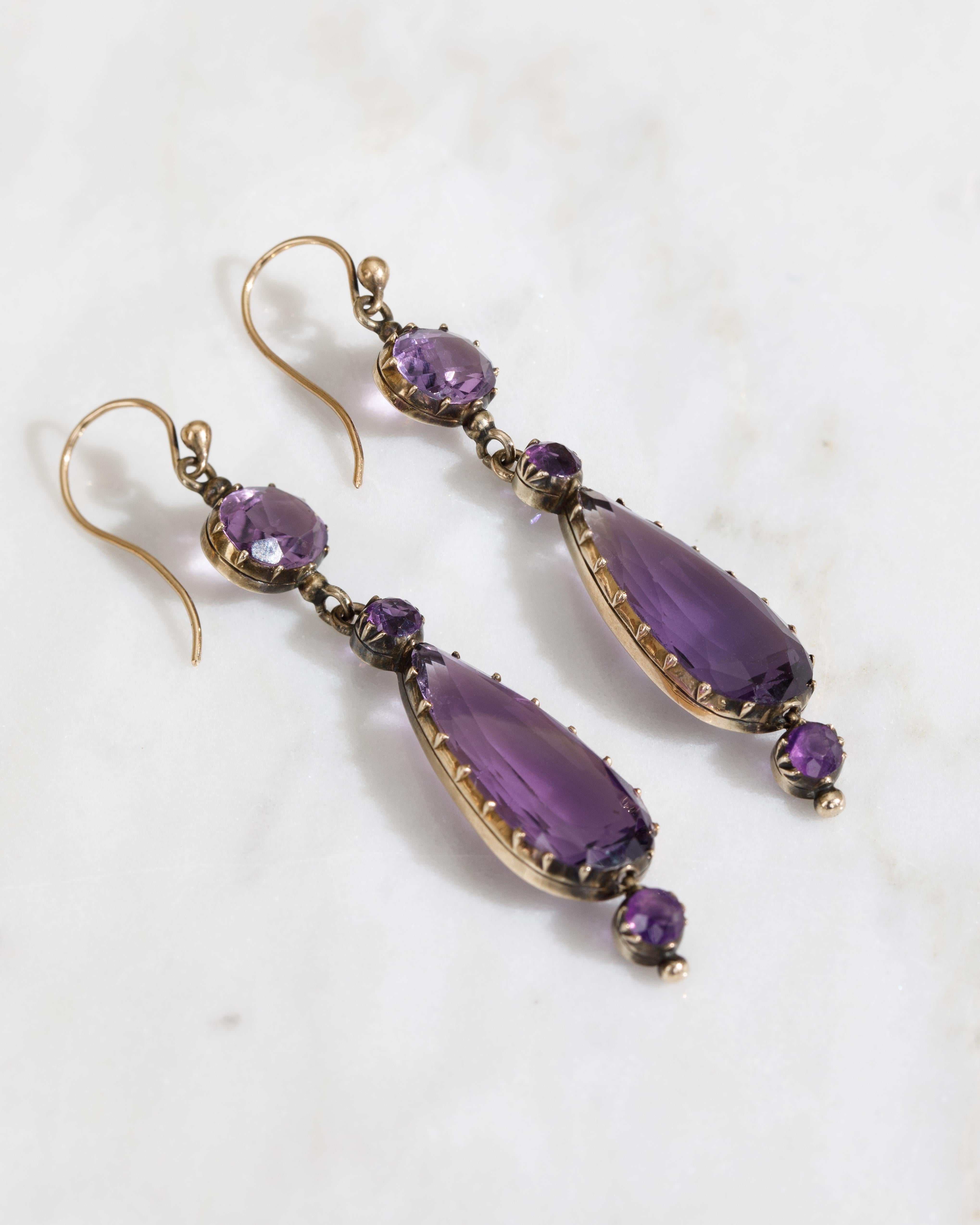 These early 19th Century Amethyst earrings feature 4 amethysts per earring, with elegant  pear cut amethysts set in delicate gold mounts, accented by smaller round cut amethyst stones. The intricate craftsmanship highlights the deep purple hues, and