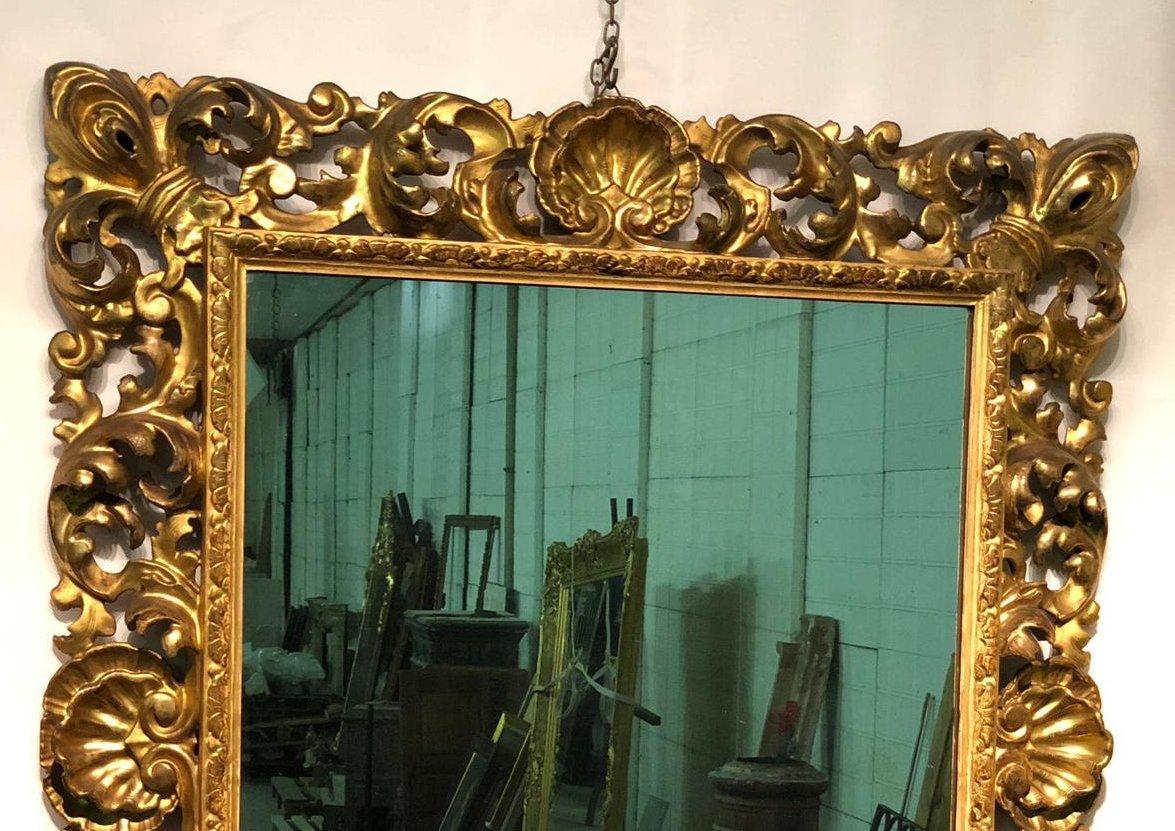 Sumptuous early 19th century carved and gilt-wood Italian mirror. The masterfully carved and carved frame is gilded with gold leaf and consists of an elaborate design that unfolds around the thin bar that runs along the entire perimeter of the