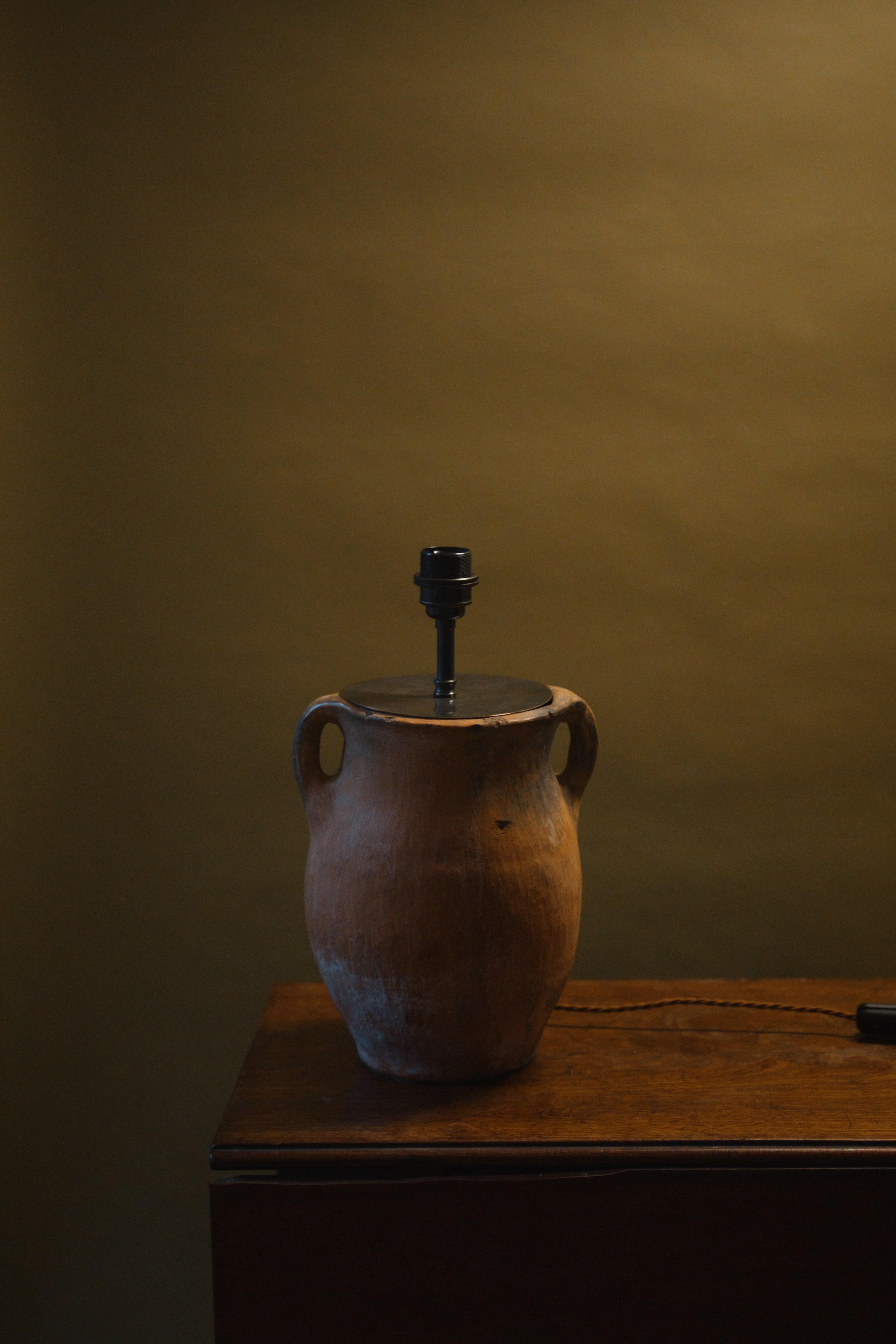 This 20th century Anatolian clay pot lamp beautifully combines artisan craftsmanship with timeless design. Handcrafted from a vintage Mediterranean clay pot with over 60 years of history, its natural patina brings character and warmth to country and