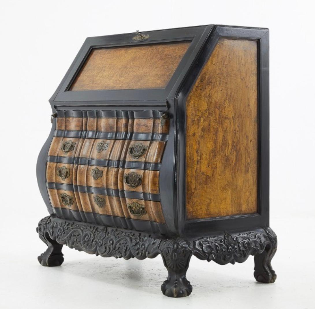 Made of burr birch and padouk wood. The shapely design showing off their exceptional craftsmanship. The beautifully carved apron base and feet, the rippled bombe shaped front with unusually fine brass original furniture , and the choice of wood