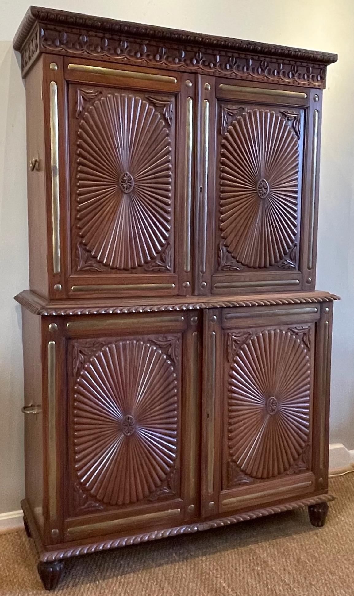 An unusual mid-19th C. Anglo-Indian intricately carved teakwood setback cabinet with extensive brass inlay and accents.