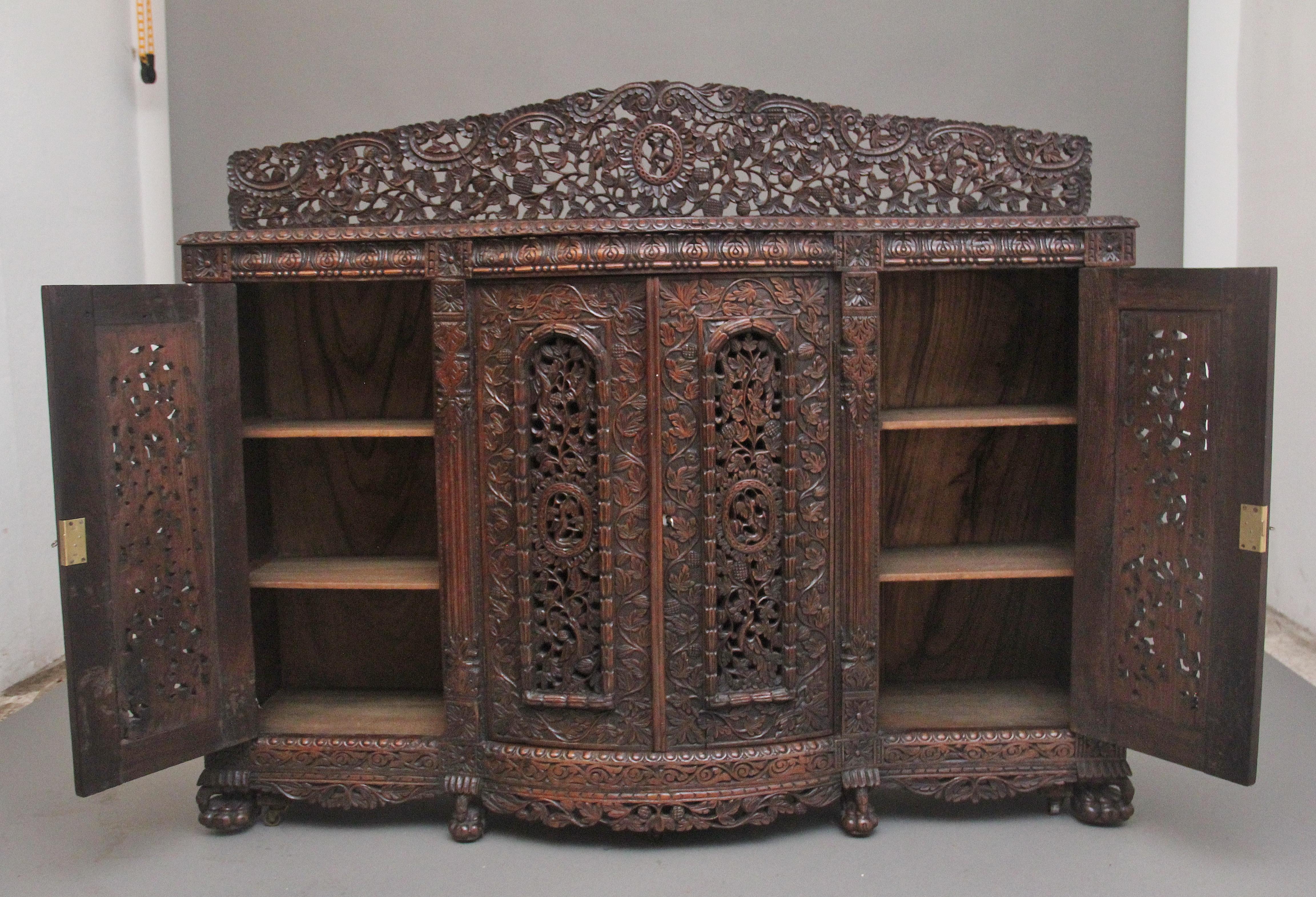 Superbe armoire anglo-indienne en bois dur sculpté du XIXe siècle, dont le joli plateau en forme de figuier présente une galerie très décorative percée et sculptée, un bord mouluré magnifiquement sculpté au-dessus d'une frise en forme avec des