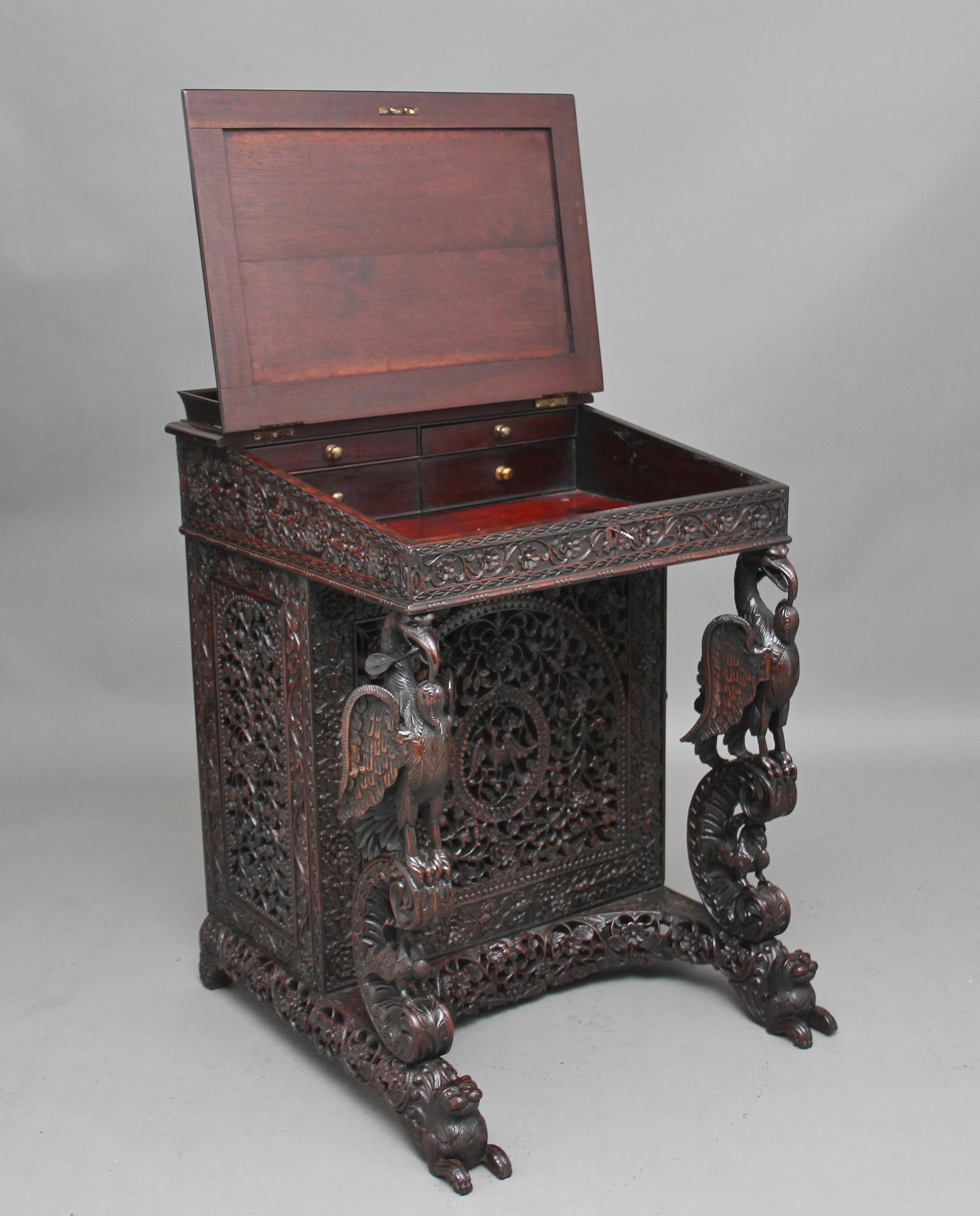 A superb quality 19th century carved teak Anglo-Indian davenport, profusely carved all over with pierced and carved flowers, foliage and vines, the sloping top having a raised gallery, a green leather writing surface decorated with blind and gold