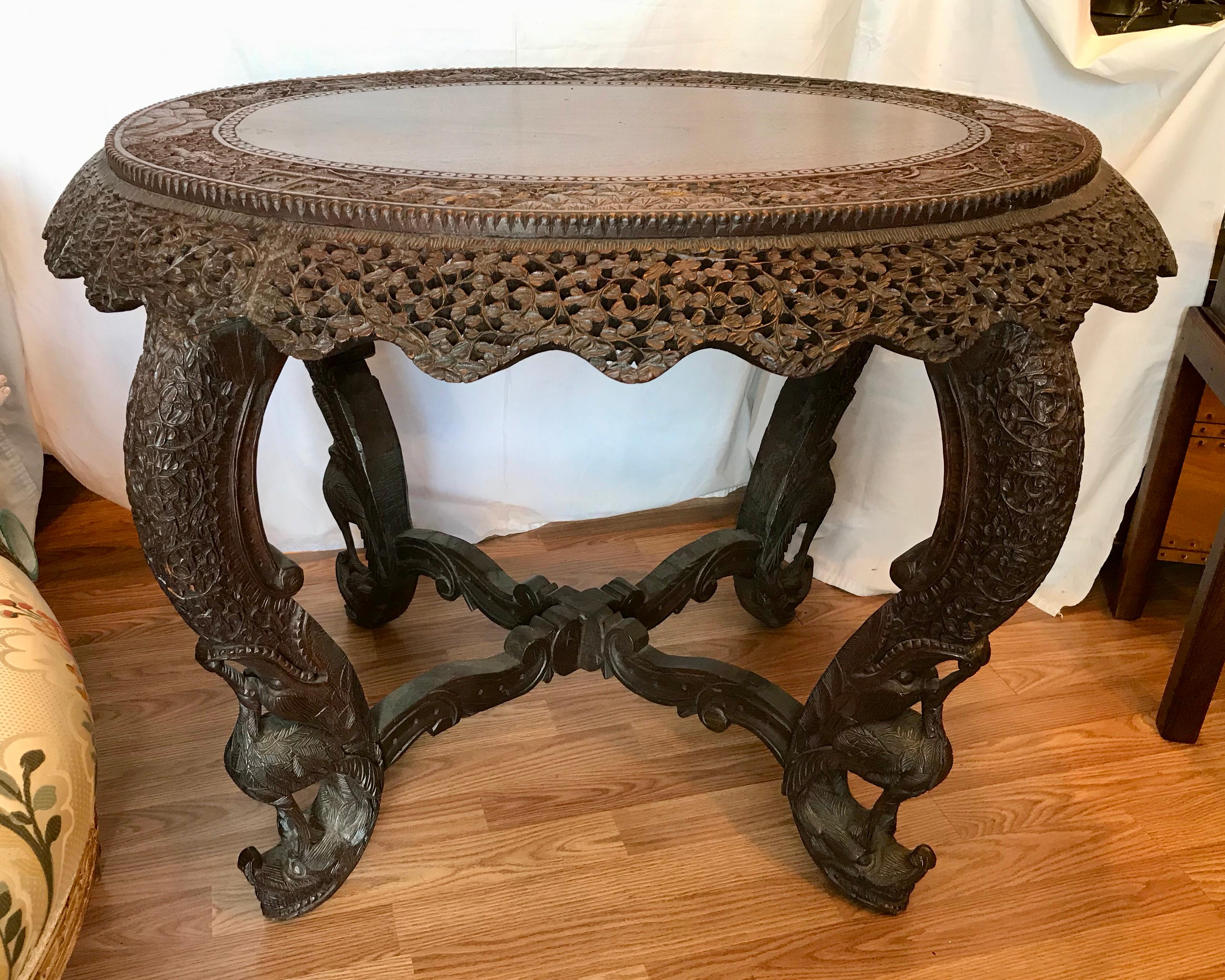 Exquisite, exceptional and elaborate hard wood carving with figures of animals embedded 
in its top. The legs are carved with birds of paradise. An outstanding and generously scaled piece.