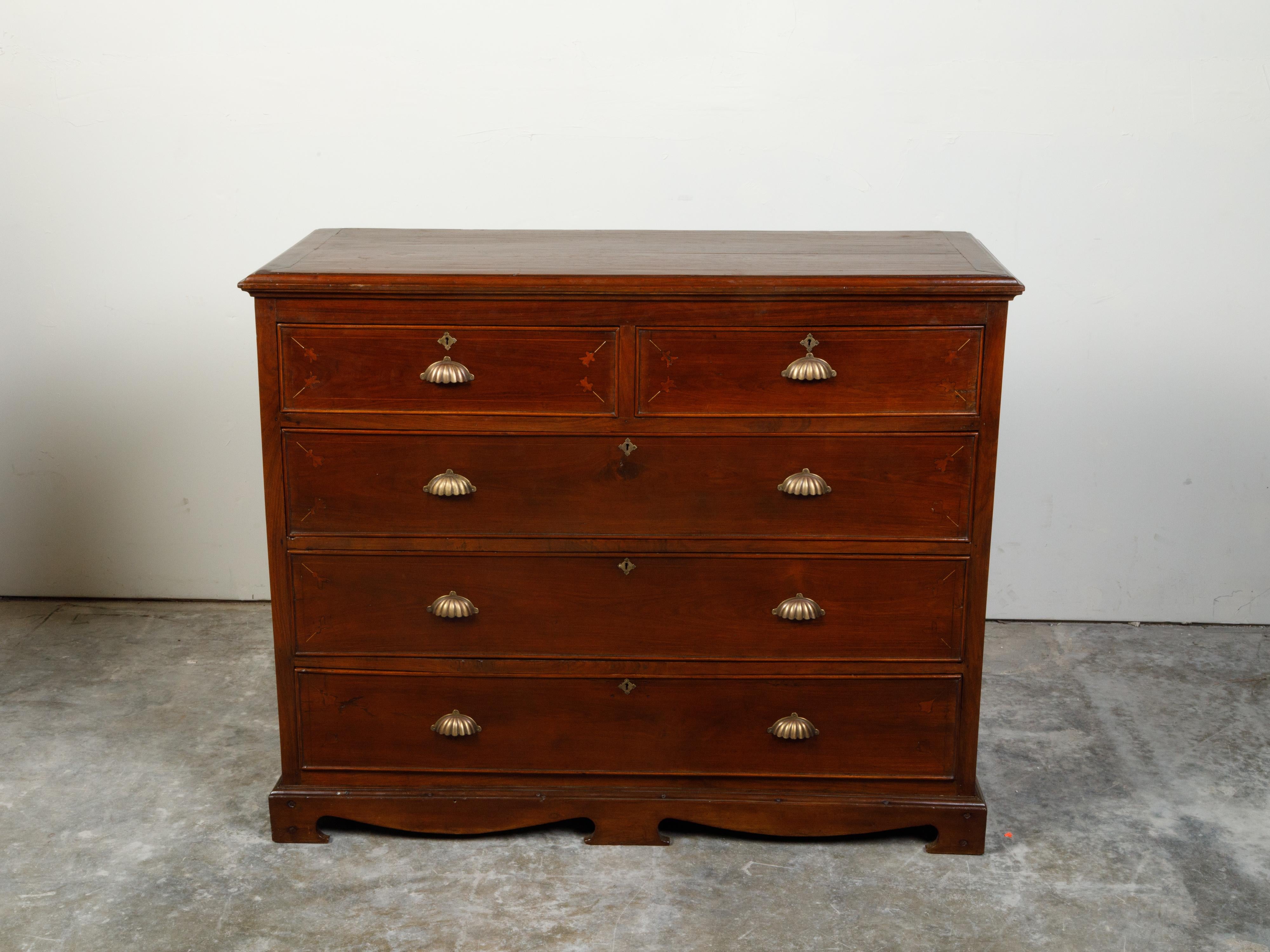 An Anglo-Indian period walnut commode from the 19th century, with five drawers, floral inlay and gadrooned hardware. Created during the 19th century, this walnut commode features a rectangular planked top sitting above two small drawers adorned with