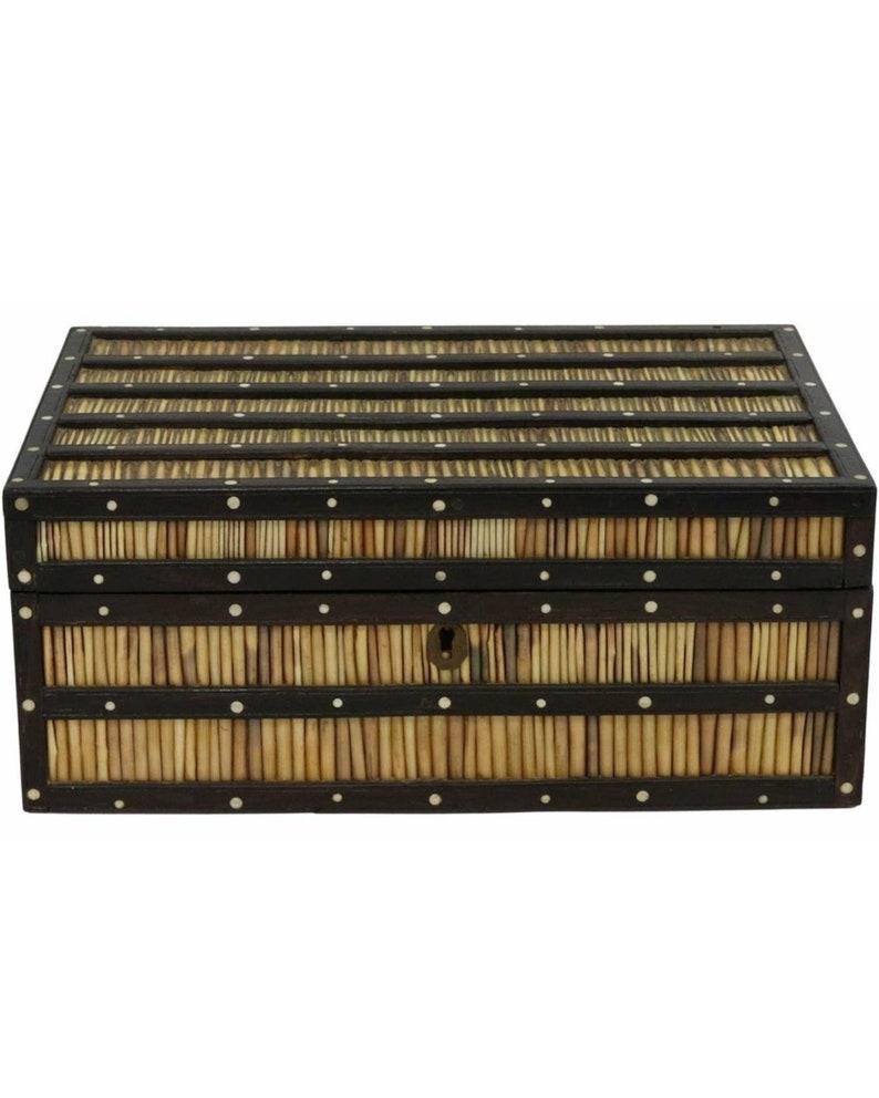 An extraordinary porcupine quill decorated ebonized wood spice box from the mid-19th century. Rarely are examples as complete as this incredible specimen.

The rectangular hinged lid box having wooden strapping, bands of striated quills between