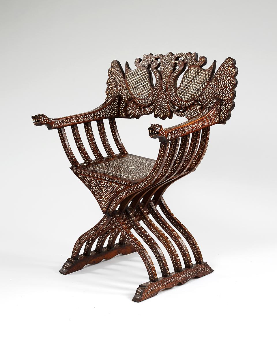 Indian rosewood and bone Savonarola arm chair, with a pierced top carved with opposing peacocks inlaid with foliate decoration, the arms terminating in leopards heads. A Moorish design for the European export market. Made in Northern India,