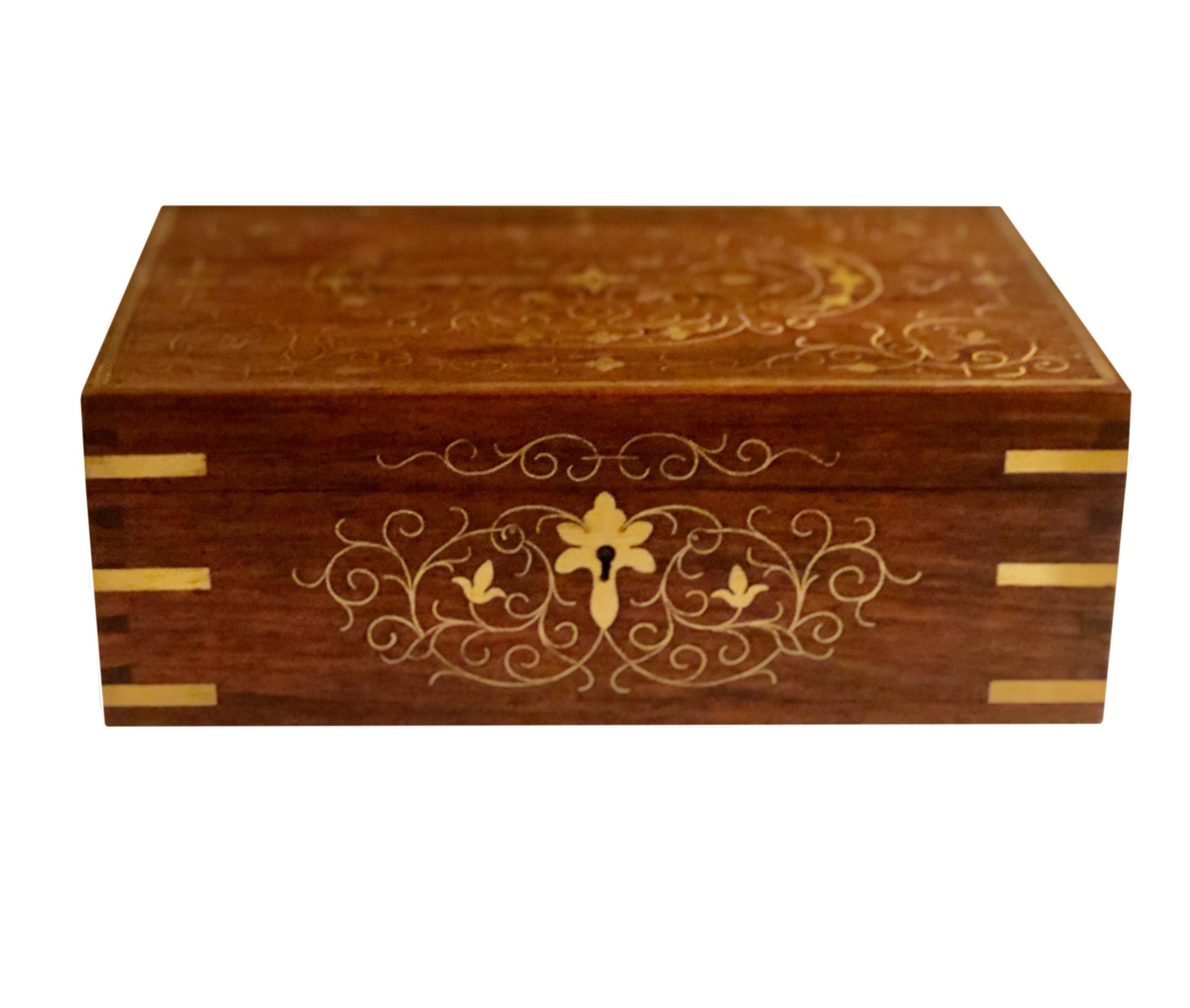 Boîte en bois de rose d'origine anglo-indienne vers la fin du XIXe siècle. Le motif doré de fleurs et de volutes sur le dessus se prolonge sur les quatre côtés, ce qui permet de l'exposer joliment sur un bureau ou une table. La boîte a deux niveaux