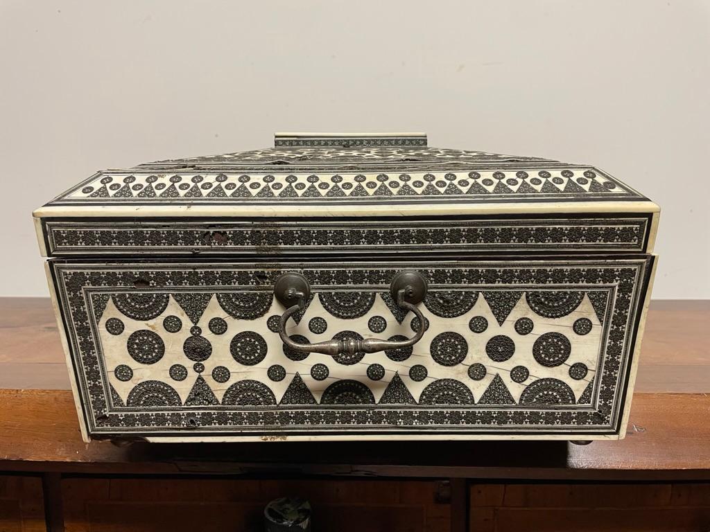 A stunning camel bone, ebony and metal inlaid sadeli work box with portable writing desk, Bombay, circa 1850.
The sandalwood body of faceted rectangular form with a hinged lid lined with violet velvet. The front drawer opening out into a velvet