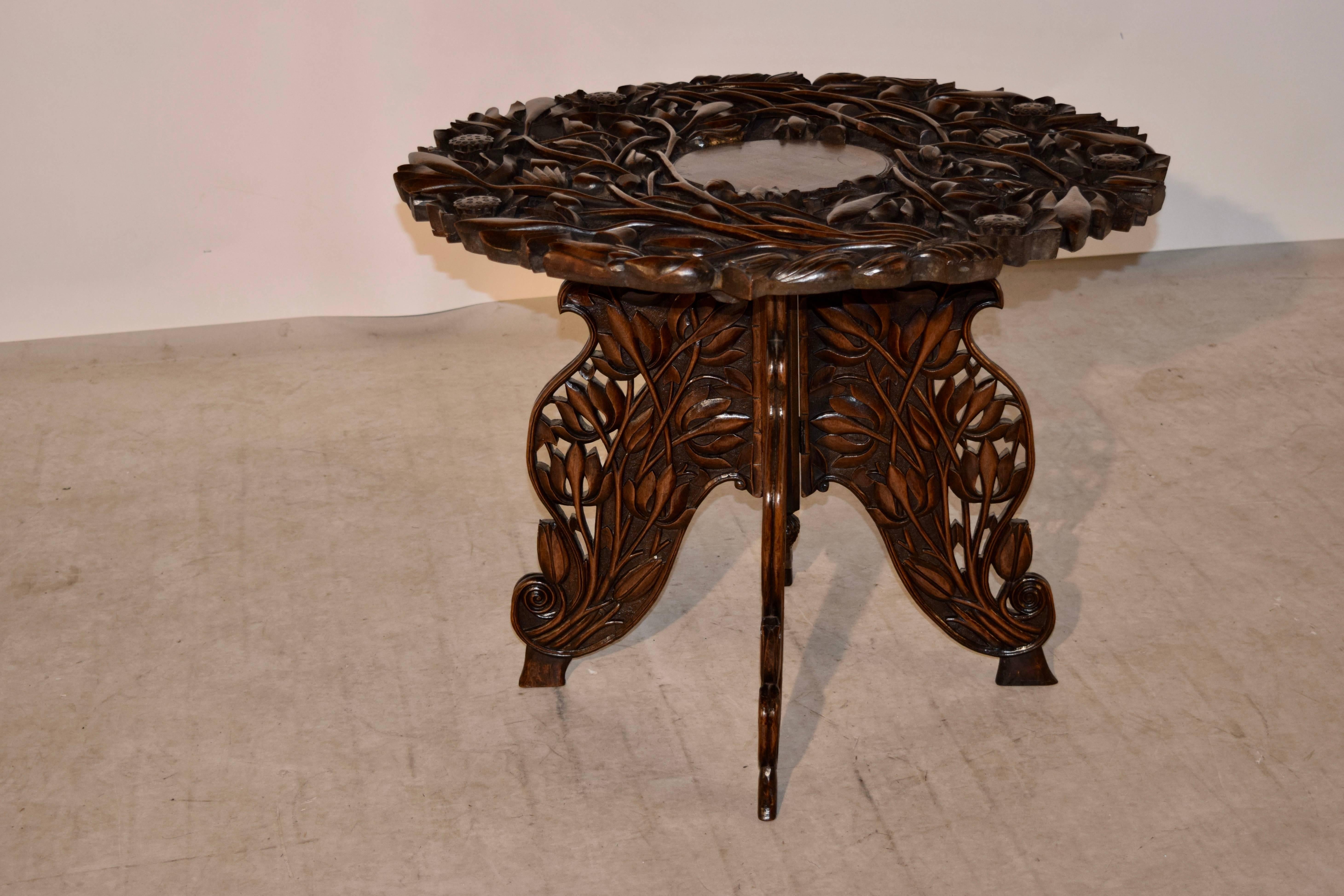 19th century Anglo-Indian side table with exquisite hand-carved designs of relieved vines and florals surrounding the top and continuing down the base and legs. The tabletop is removable and the base folds for easier transport.