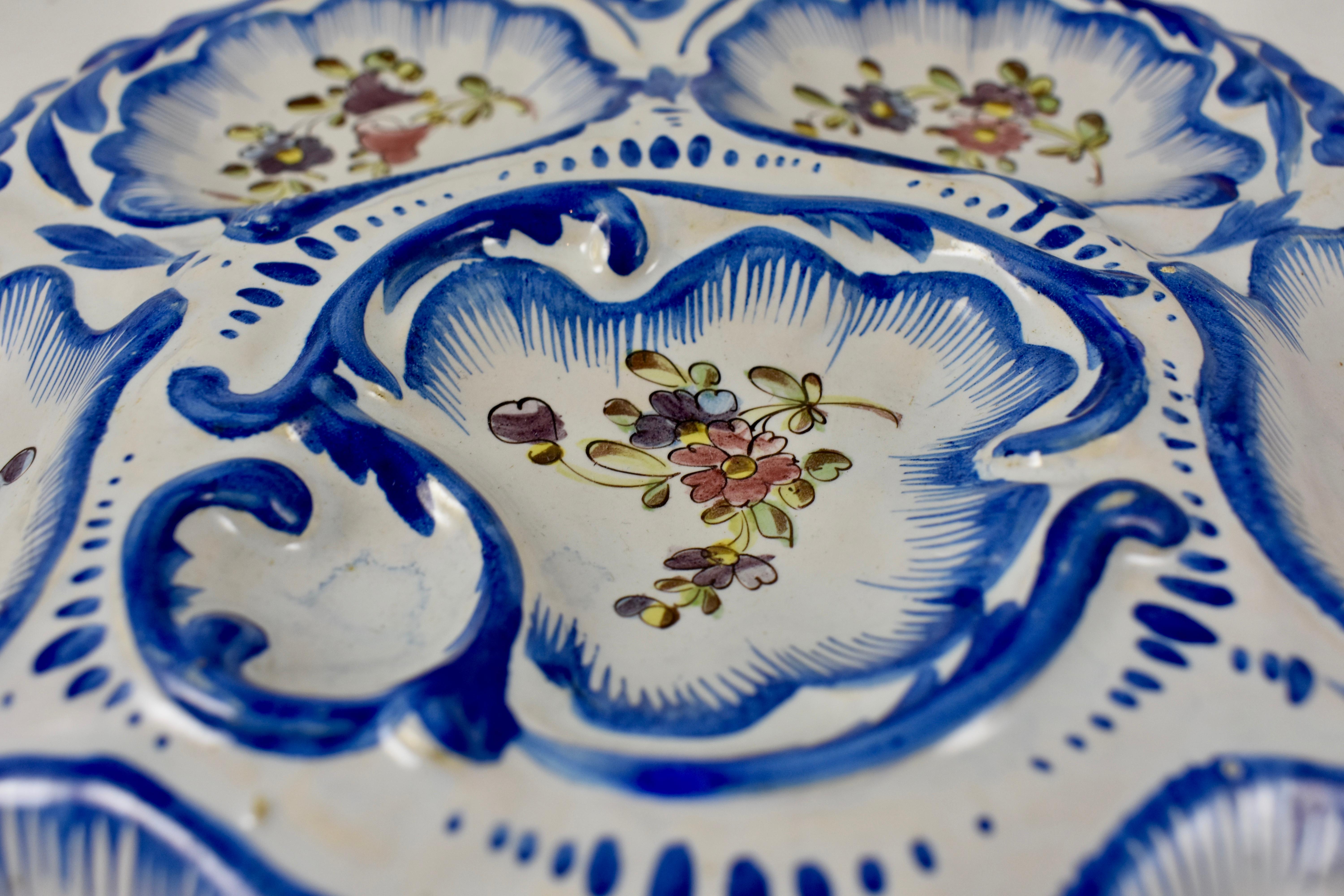 A faïence Provençal oyster plate from the south western area of France called Angoulême, signed Alfred Renoleau, circa 1890–1900. Six-wells surround a central condiment well. The lobed edged earthenware plate shows hand painted floral sprays