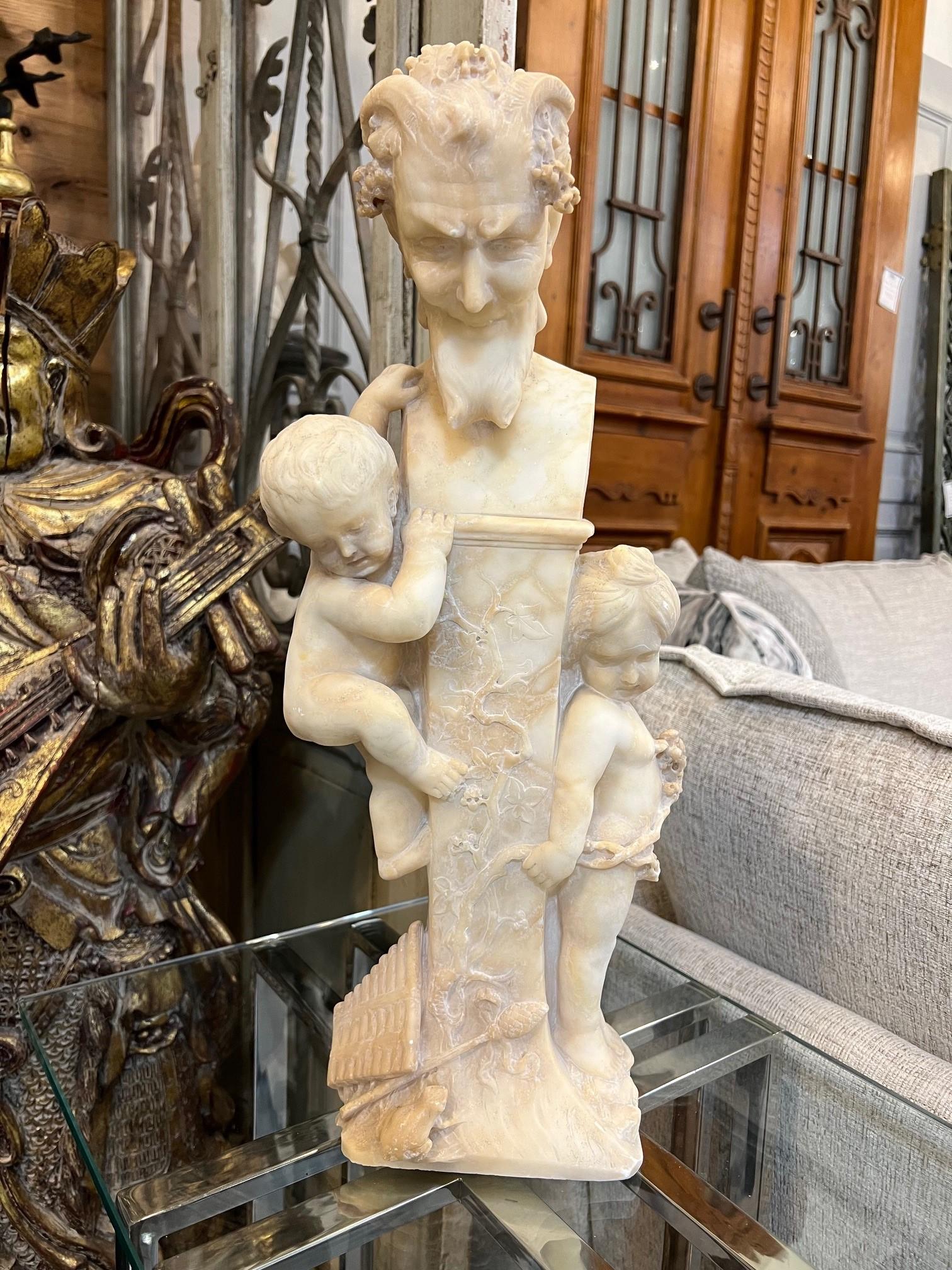 An antique Italian alabaster bust of Pan on a pedestal with two small children sculpture. Pan not being a major god was still a significant figure in Greek mythology. He was the god of shepherds, music, and fertility, and he was often depicted as a