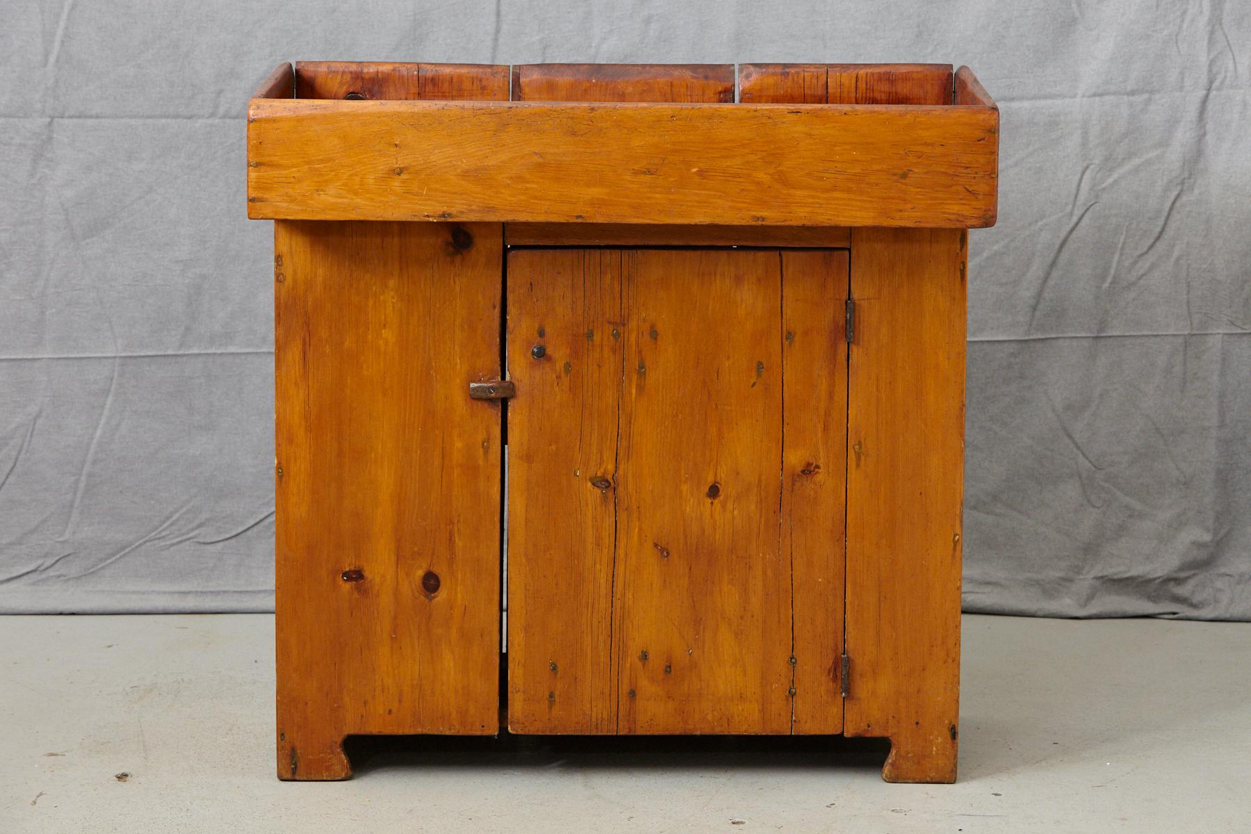 19th century antique American primitive pine dry sink. Solid and sturdy construction with a beautiful patina, one font door and one shelf, puristic, minimal hardware.
Works perfectly as a bar with a large surface and a high edge.
Measures: Depth