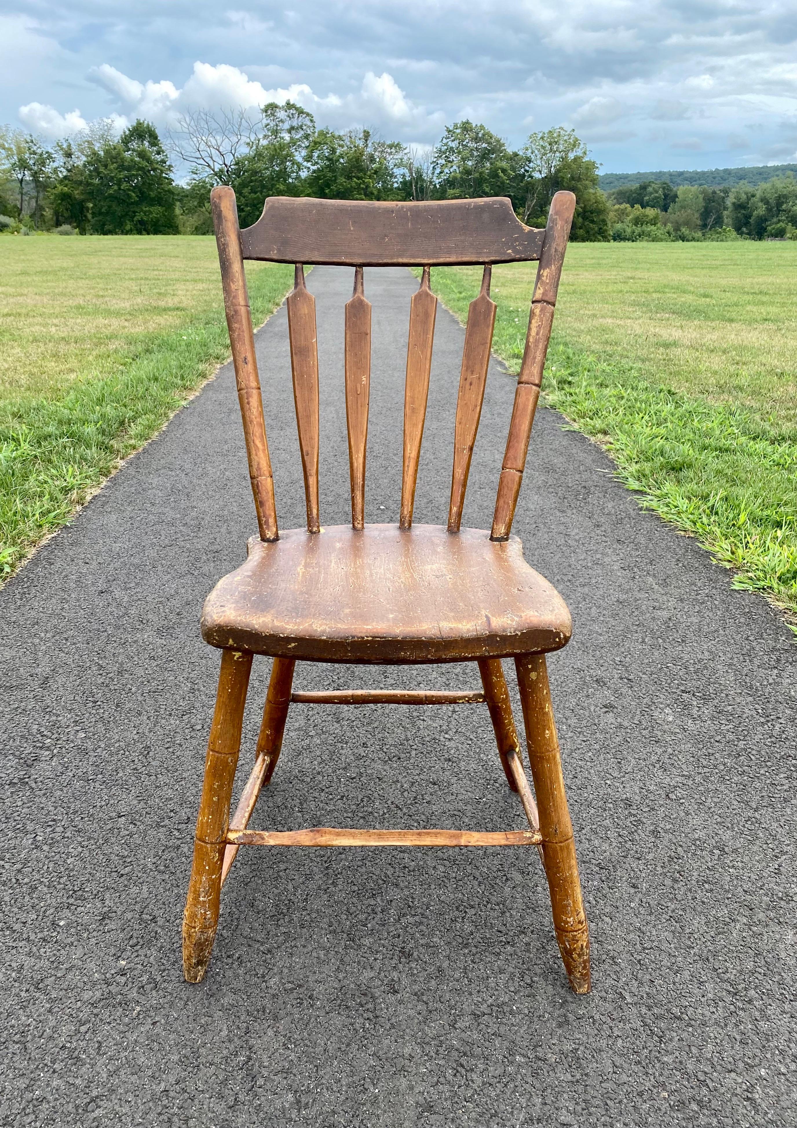 19th century antique arrow back spindle Windsor accent side chair, circa early 1800's. This charming hand carved chair features its original finish with beautiful patina. A charming piece to display in an entrance hallway, a bathroom with a stack of