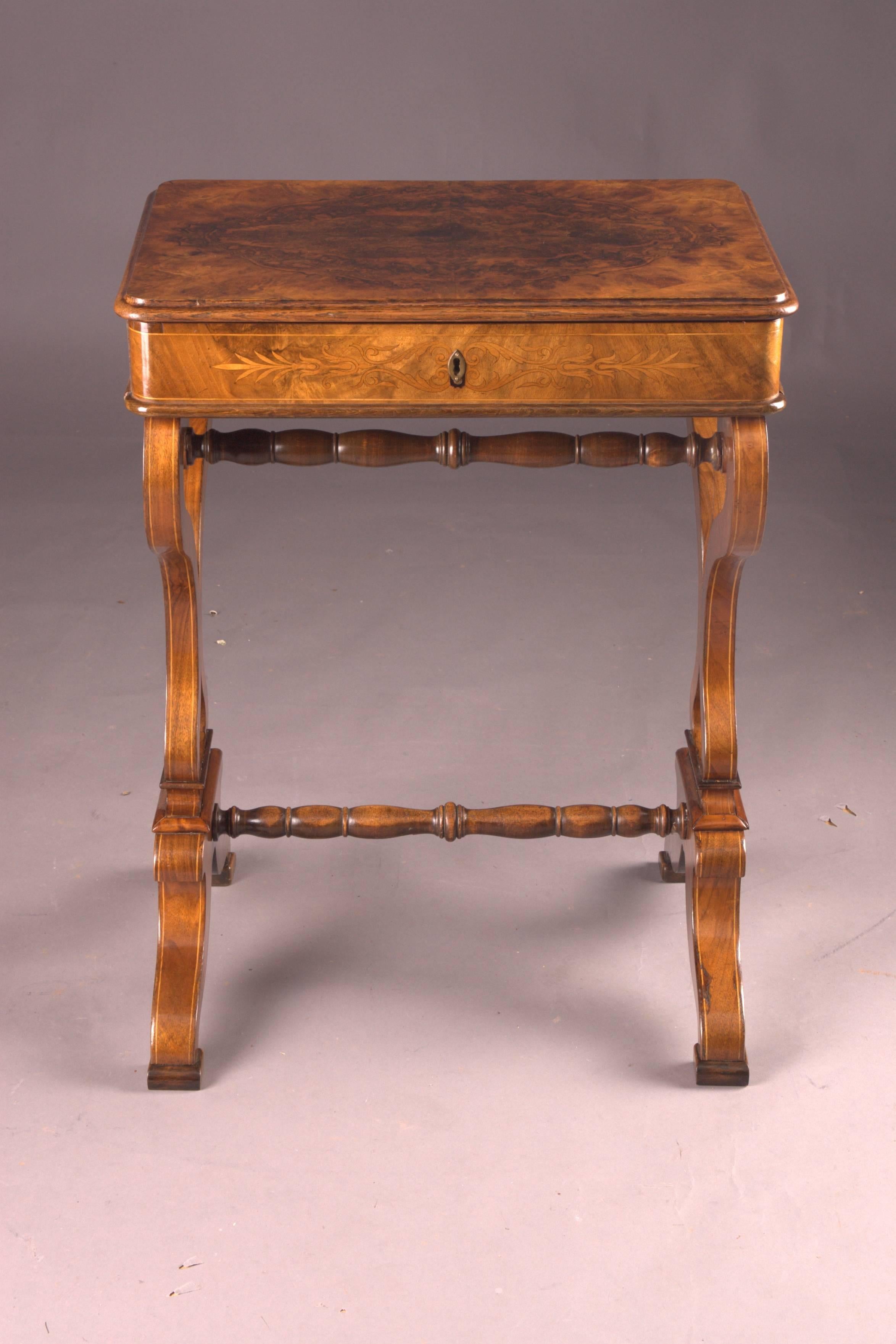 Walnut root on solid pinewood. Rectangular body with slightly overlapping hinge lid. Drawer inside with richly divided compartment. Stands on heart-shaped sides, which are connected in the middle with a turned column.

Root veneer with Classic