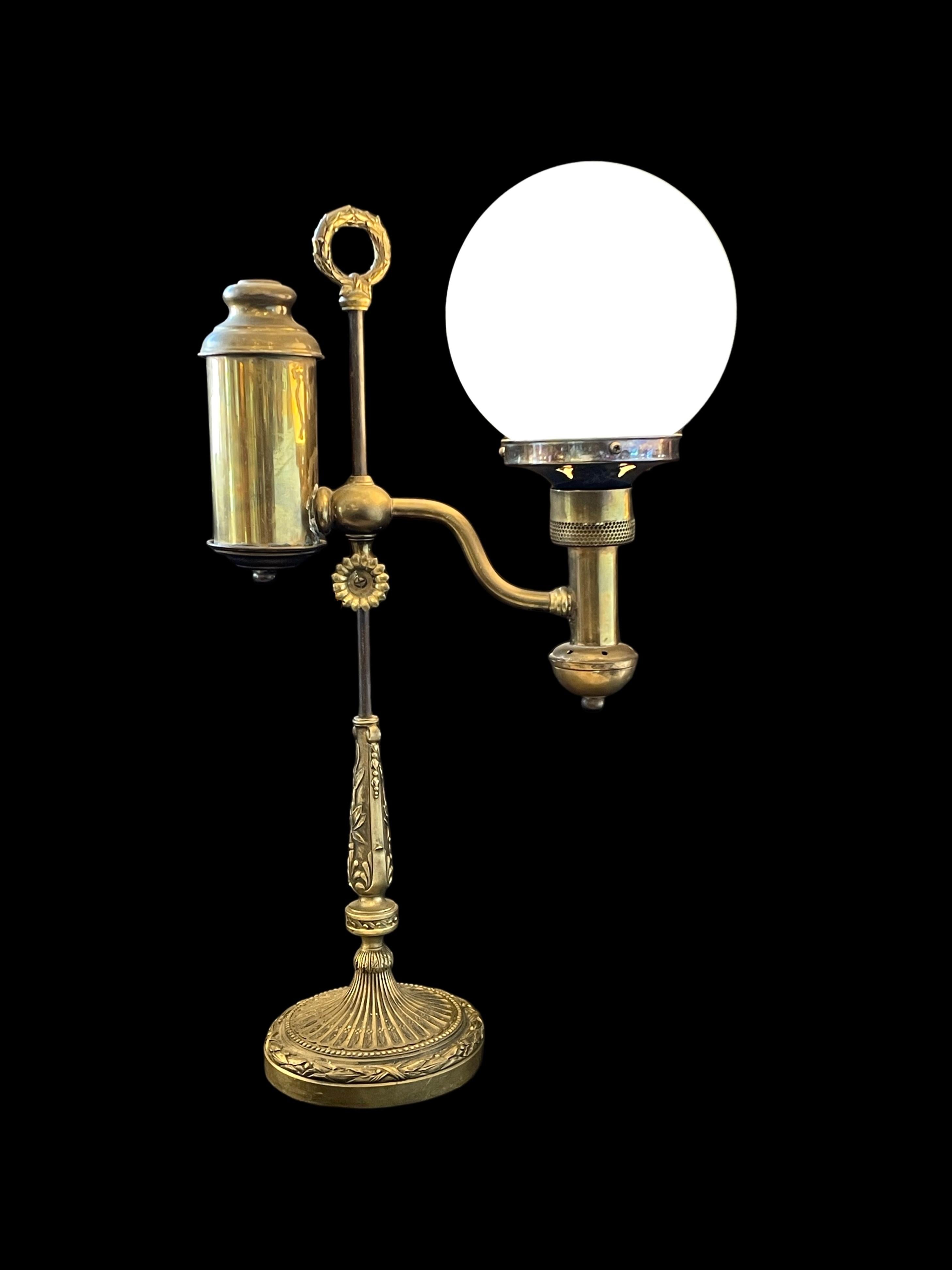 Cette exquise lampe à huile convertie Rise & Fall en laiton antique du XIXe siècle est une pièce d'apparat étonnante, alliant l'élégance intemporelle à la fonctionnalité.

En son cœur, un magnifique globe en verre opalin repose gracieusement sur son