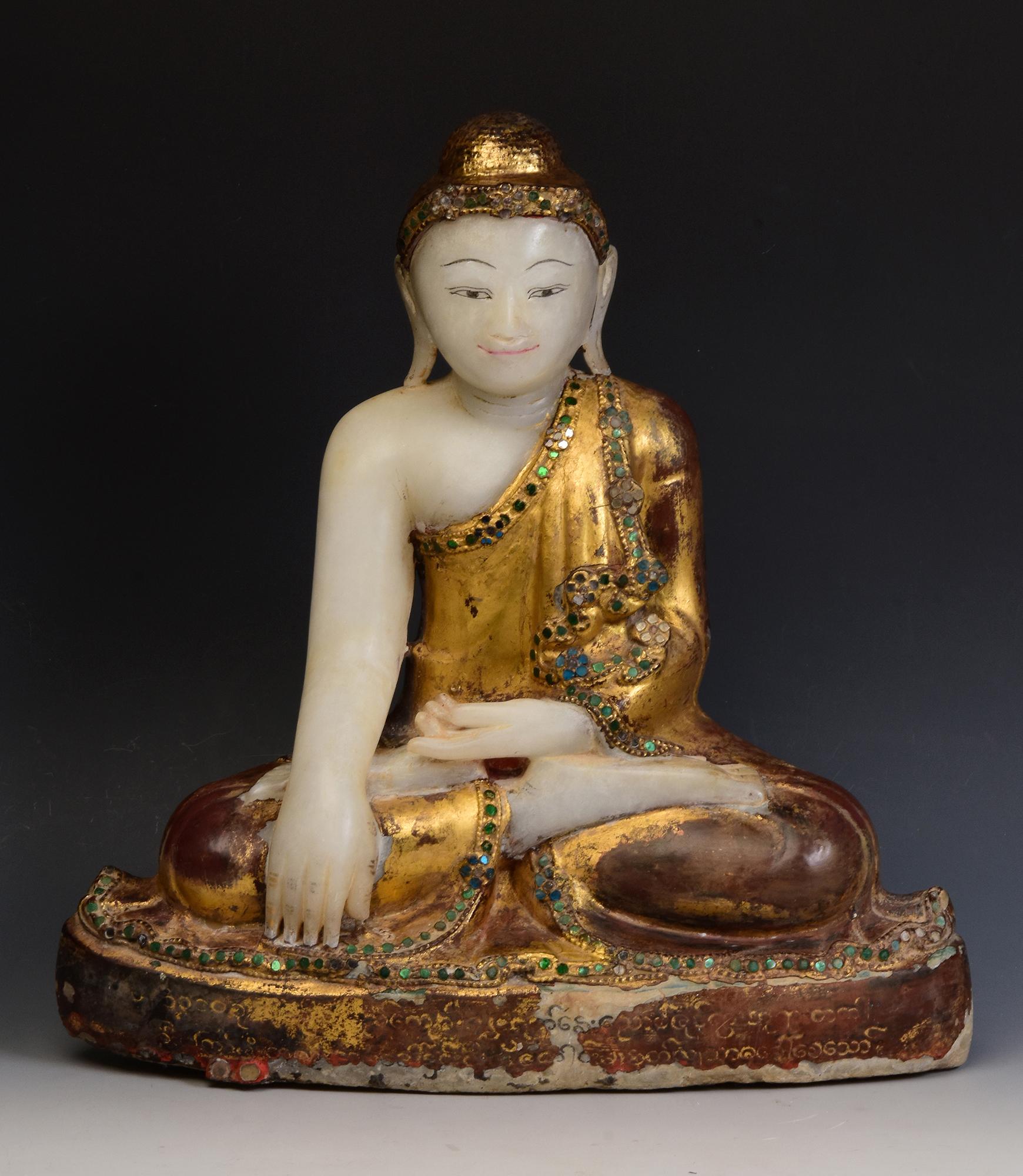 Antique Burmese alabaster Buddha sitting in Mara Vijaya (calling the earth to witness) posture on a base, with original inlay of colorful glass pieces on the headband, borders of the robes and gilding.

Age: Burma, Mandalay Period, 19th