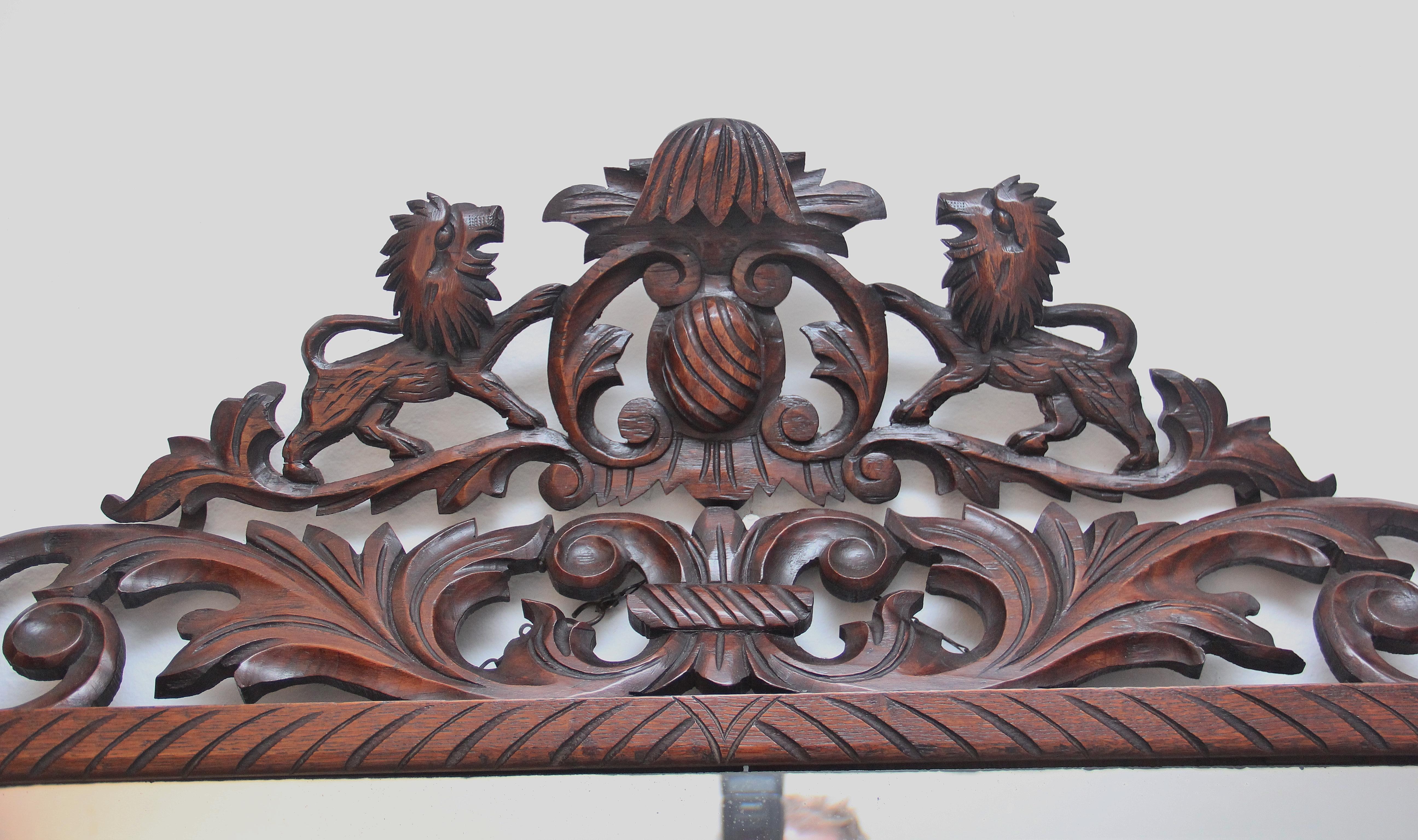 19th century highly decorative carved oak wall mirror, the bevelled edge glass mirror having a wonderfully intricate carved oak frame incorporating bold floral design, central motif at the top flanked either side by lions. In excellent condition and