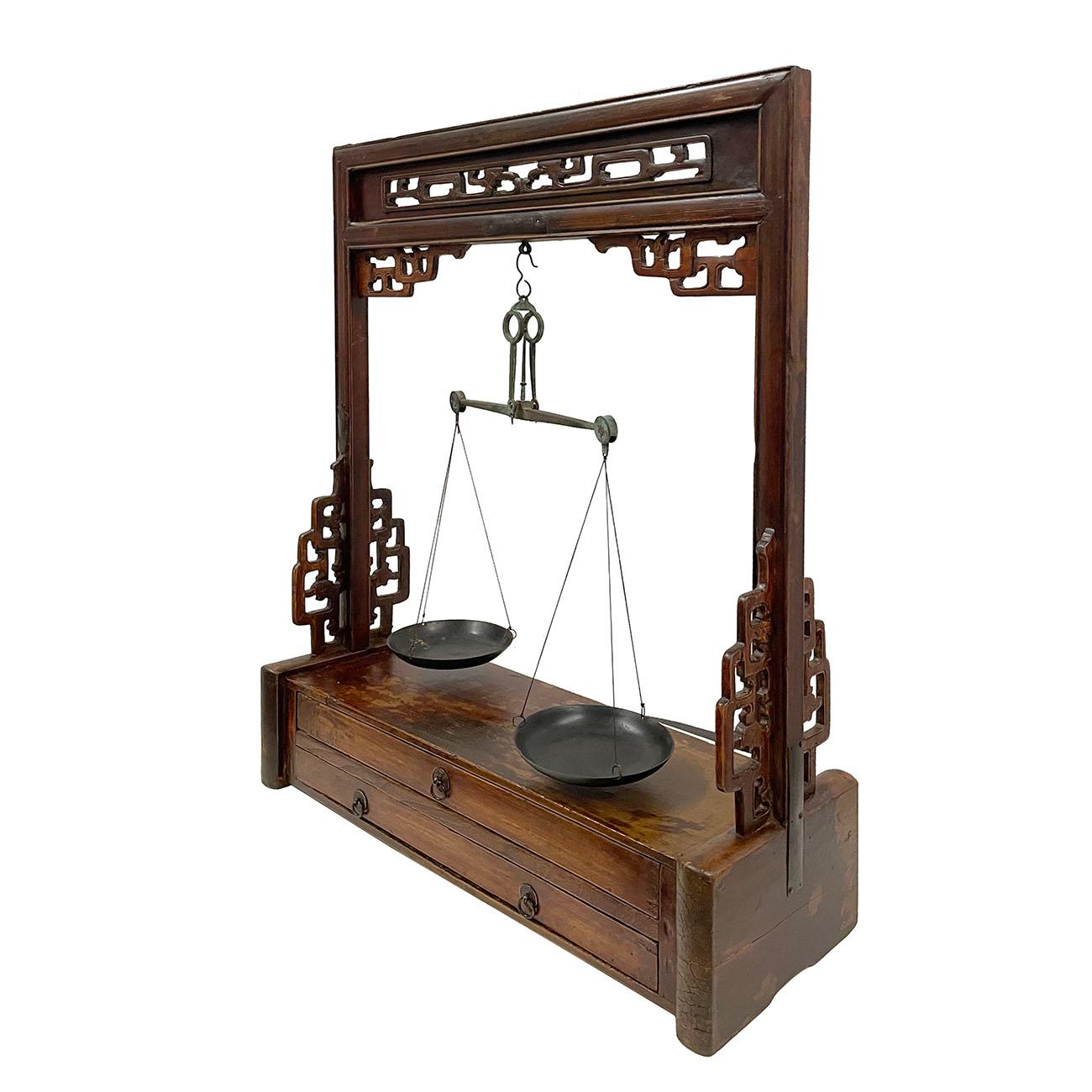 Beautiful Chinese carved wood apothecary balance scale stand with a set of 30 pieces scale weights and storage drawers. It features beautiful carved fretwork on the top and sides featuring brass metal hardware and trim. It has two drawers on the