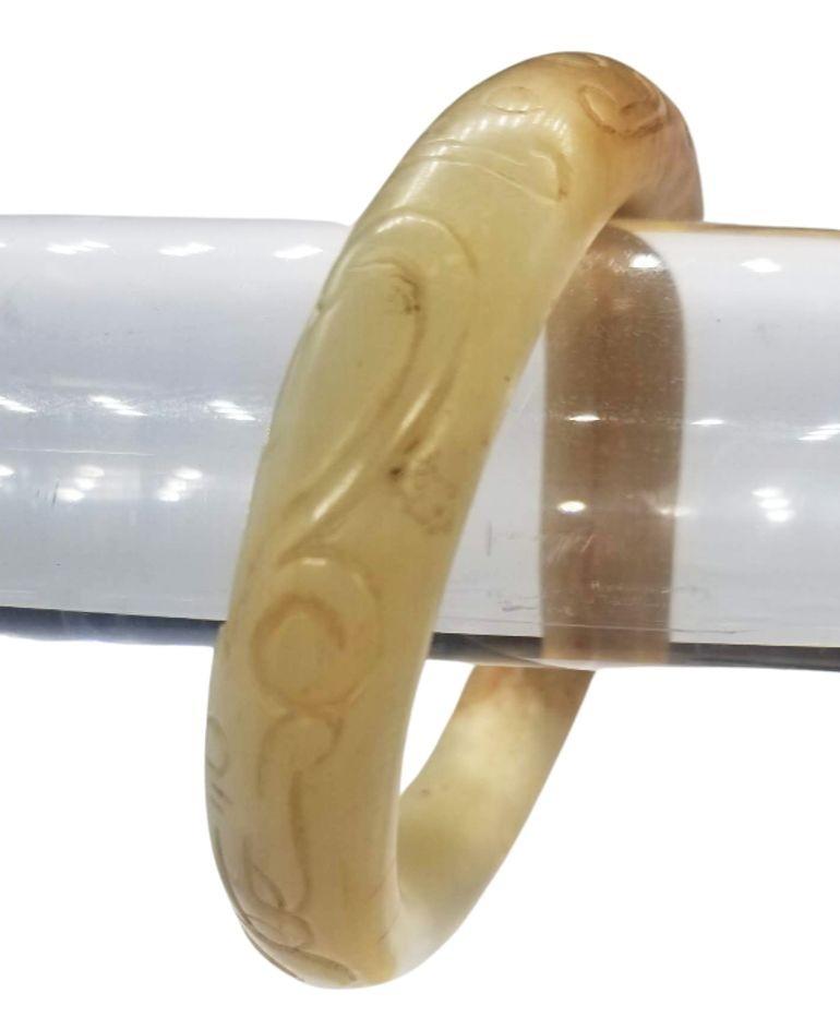 Plongez dans l'attrait de l'histoire avec ce captivant bracelet de jade antique chinois sculpté à la main. Fabriqué avec habileté et précision, le bracelet de jade présente un mélange enchanteur de couleurs et de textures, mettant en valeur la