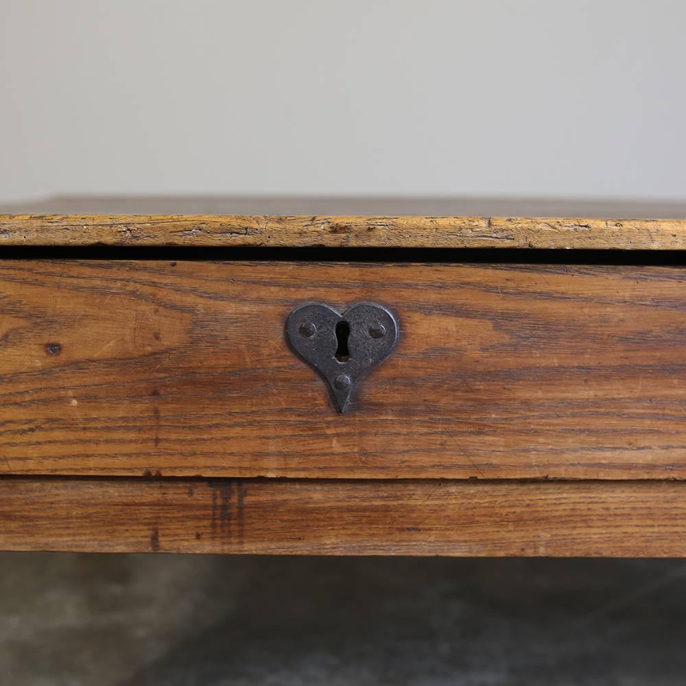Designed to last for centuries, this 19th century rustic antique country French ash coffee farm table was fashioned from solid planks of old-growth French ash with pegged mortise and tenon joinery and two convenient drawers making it as functional