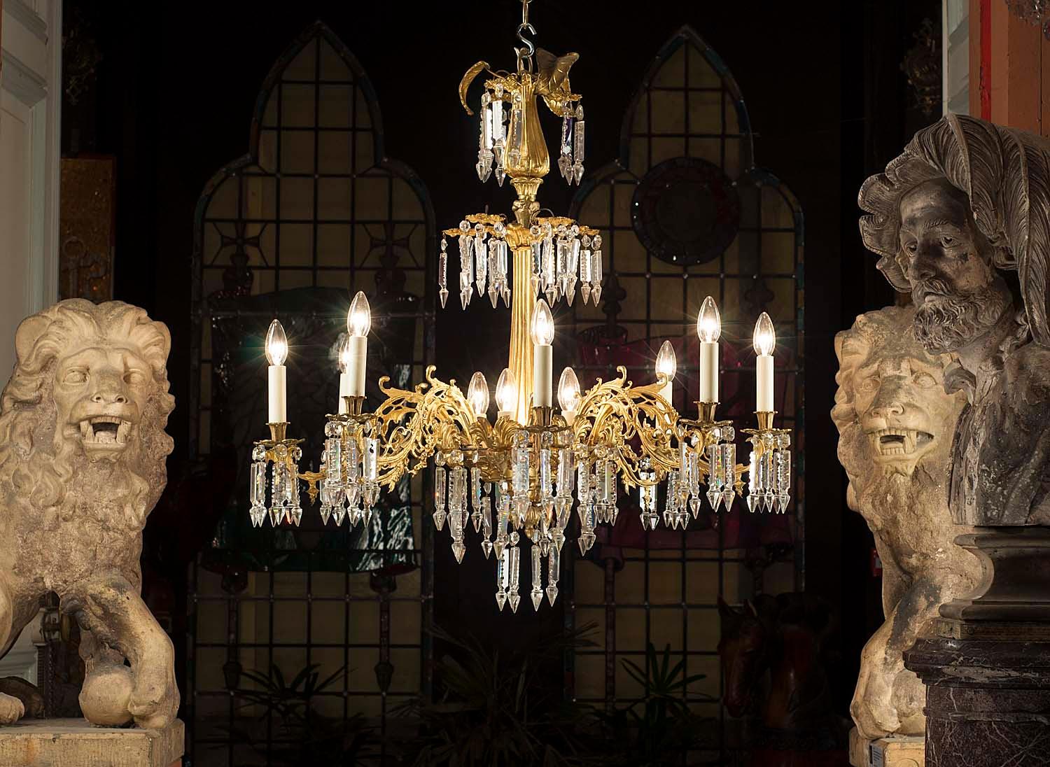 An elaborate 19th century antique eight branch gilt bronze chandelier with fluted and tapering central baluster column, hung and adorned with cut crystal spear pendants and prism drops. Converted to electricity. 
Mid-19th century.