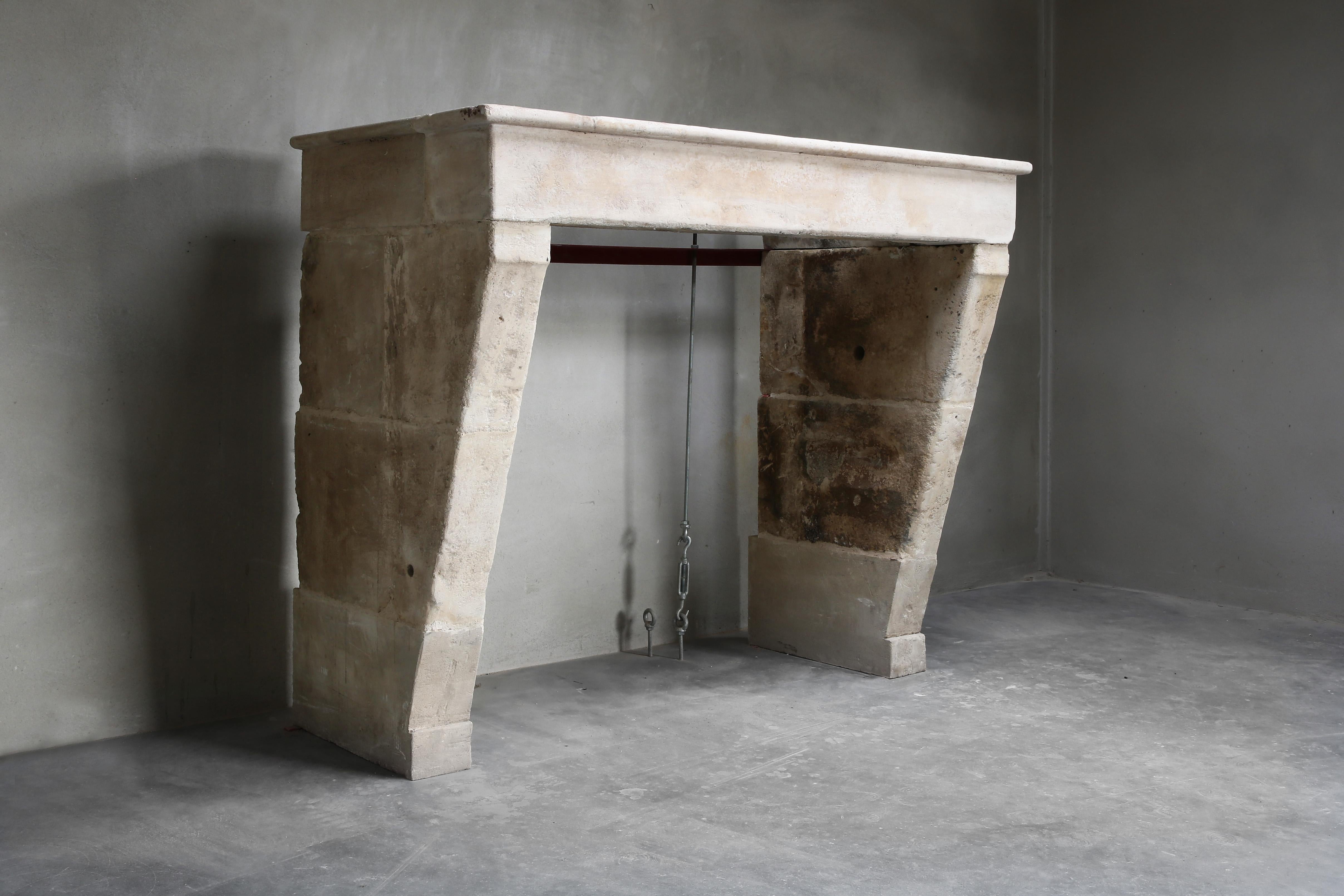 Beautiful simple antique French limestone fireplace from the 19th century in the style of Campagnarde. The legs are straight but bent inwards. The warm color scheme and proportions of this fireplace ensure atmosphere and authenticity. Due to the
