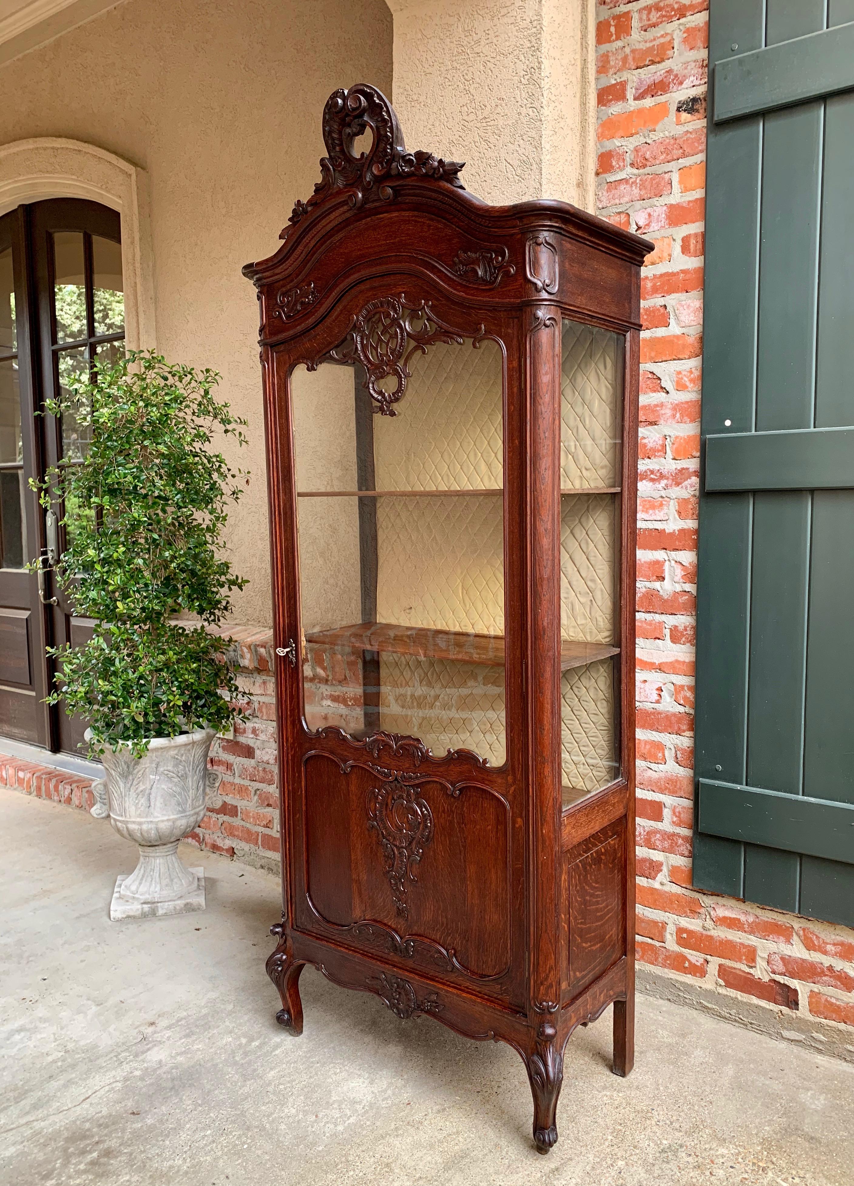 Direct from France, a stunning antique French display cabinet with gorgeous hand carvings from top to bottom!
~ Solid hand carved upper crown sits above the arch dome top and features open flourish and carved floral accents
~ Carved details on the