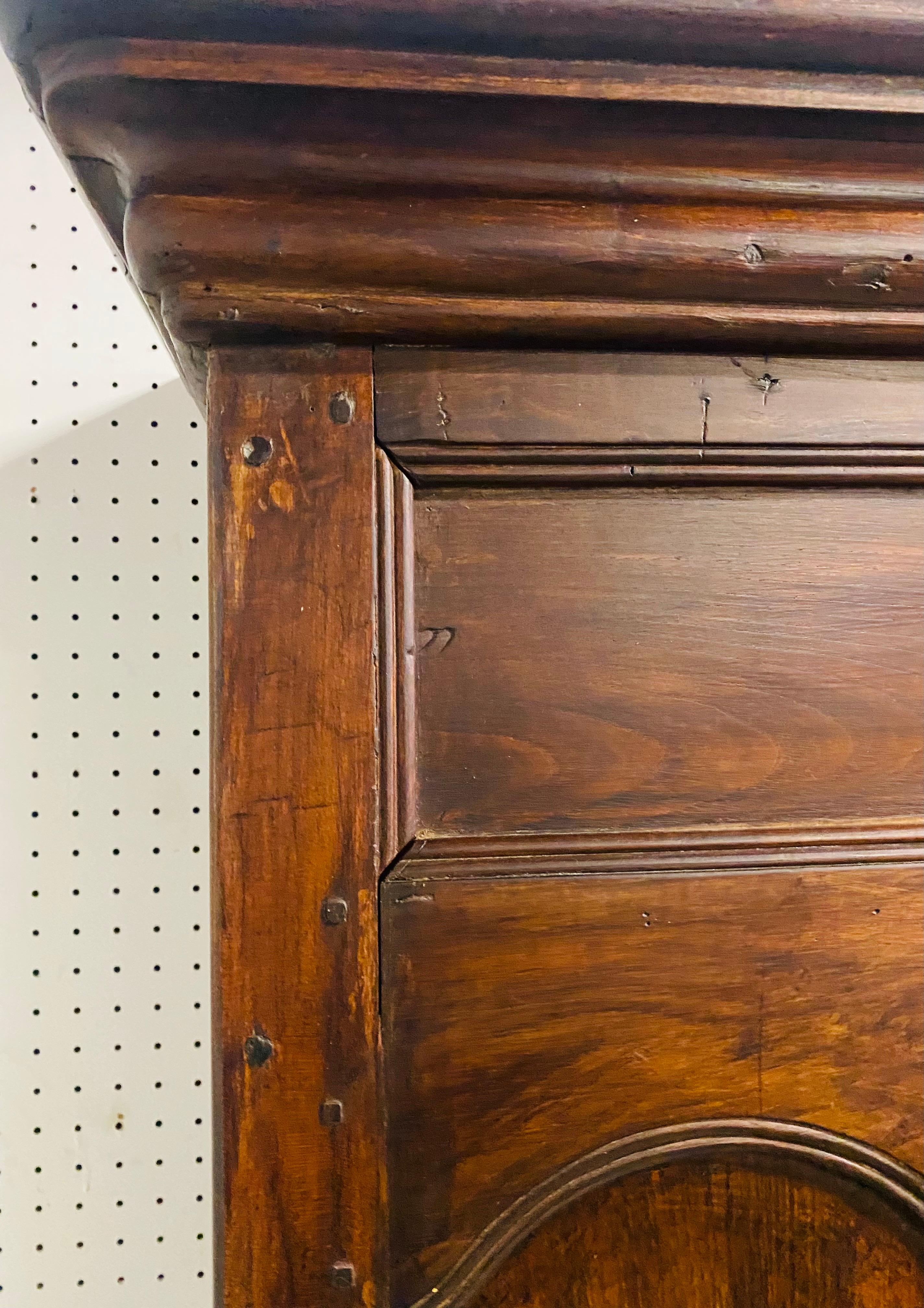 This is an antique late 19th century French country Hand crafted cabinet. This dark walnut hand carved cabinet has beautiful scrollwork at the top with shelves in the center. This cabinet features too small side cabinets on either side with doors