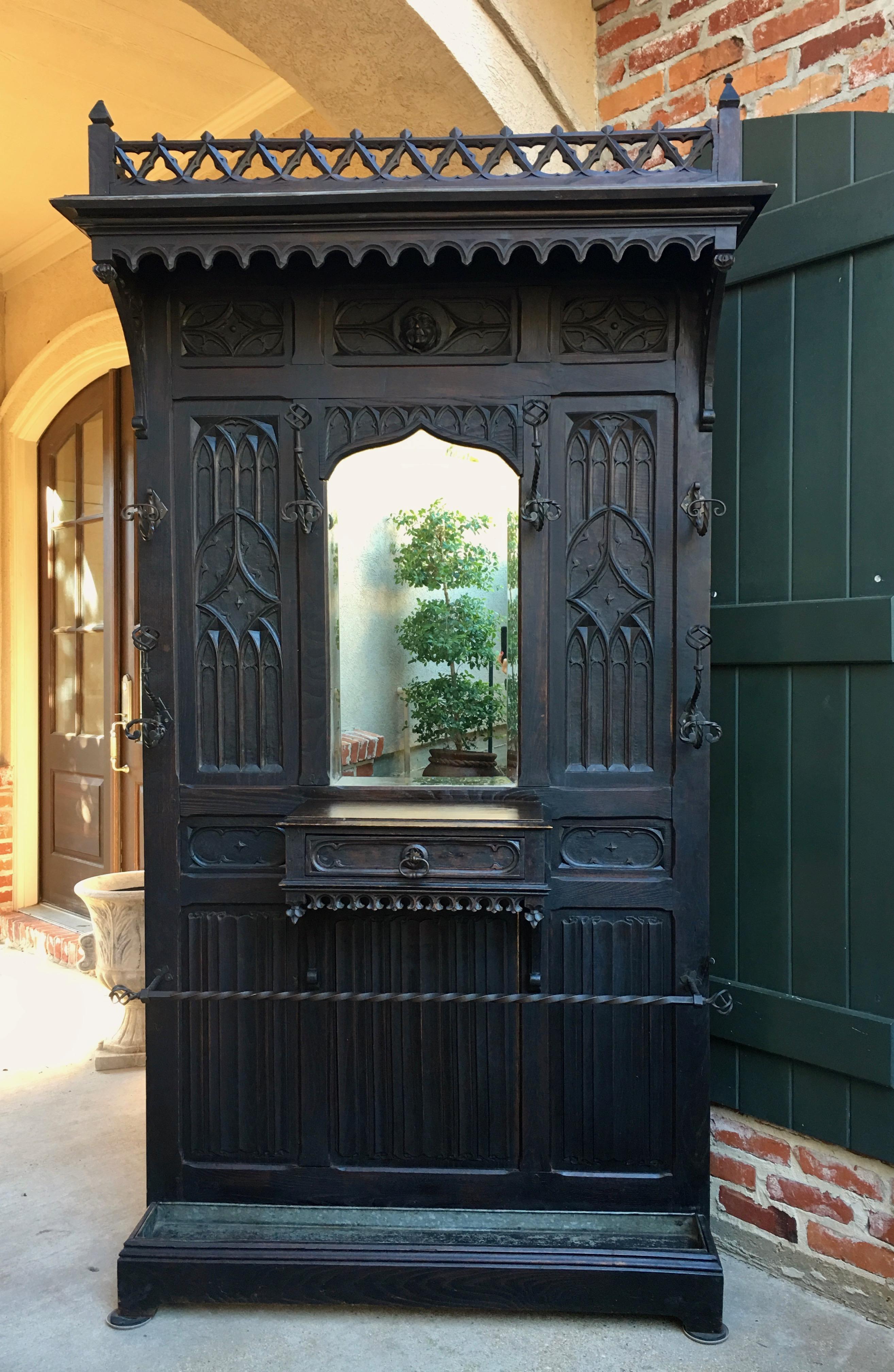 Direct from France, a majestic, almost 8 ft. tall antique French carved oak hall tree with center mirror and Gothic style!
~Open carved upper crown with open scalloped crown trim across the entire front and sides~
~Outstanding Gothic carved