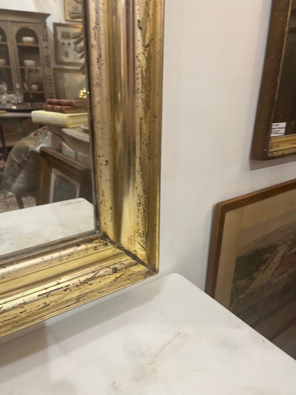 This 19th-century Antique French Louis Philippe Gilt Wall Mirror possesses timeless elegance. Crafted in the Louis Philippe style, it showcases intricate gilt detailing along the frame, reflecting the opulence of the era. The mirror's generous size